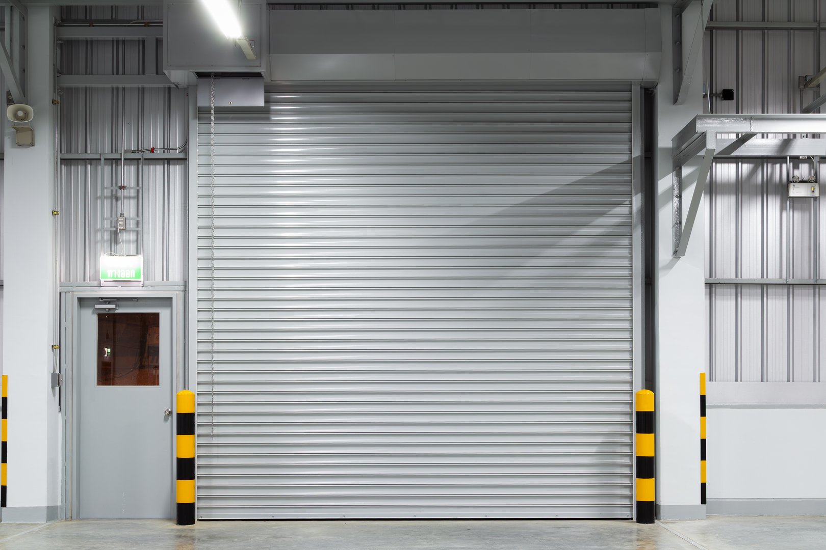 Shutter door or roller shutter inside industrial building at front. To construction for entrance of commercial, industrial building i.e. warehouse, factory, garage, hangar or shop suit for background.