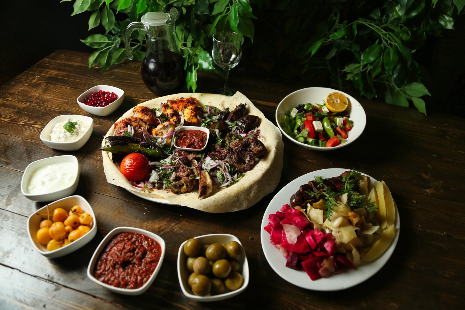 A wooden table set with a variety of Turkish meze dishes, including grilled meat, salad, and dips.