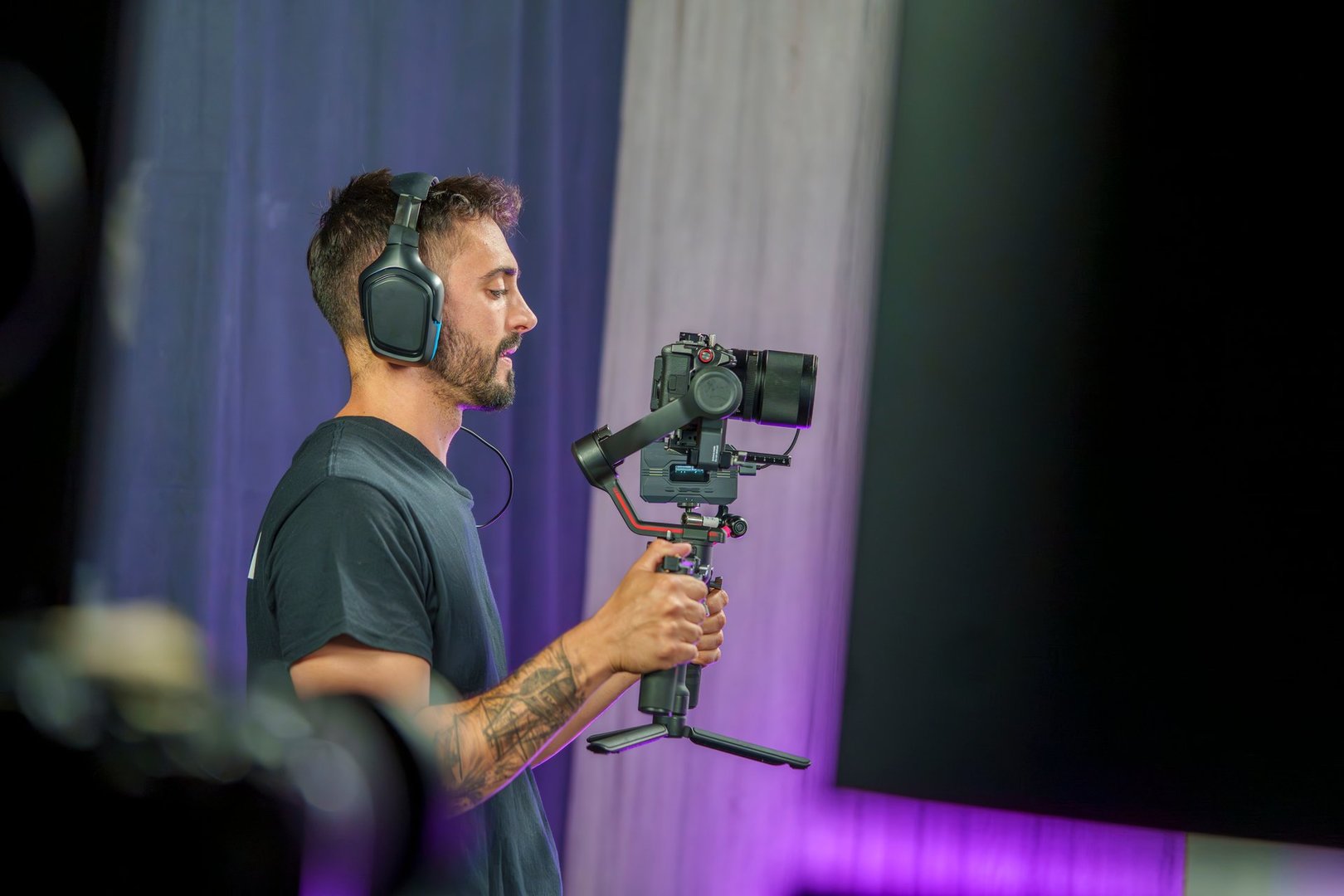 Young Male Camera Operator Using a Gimbal for Filming on a Professional TV Set with Headphones