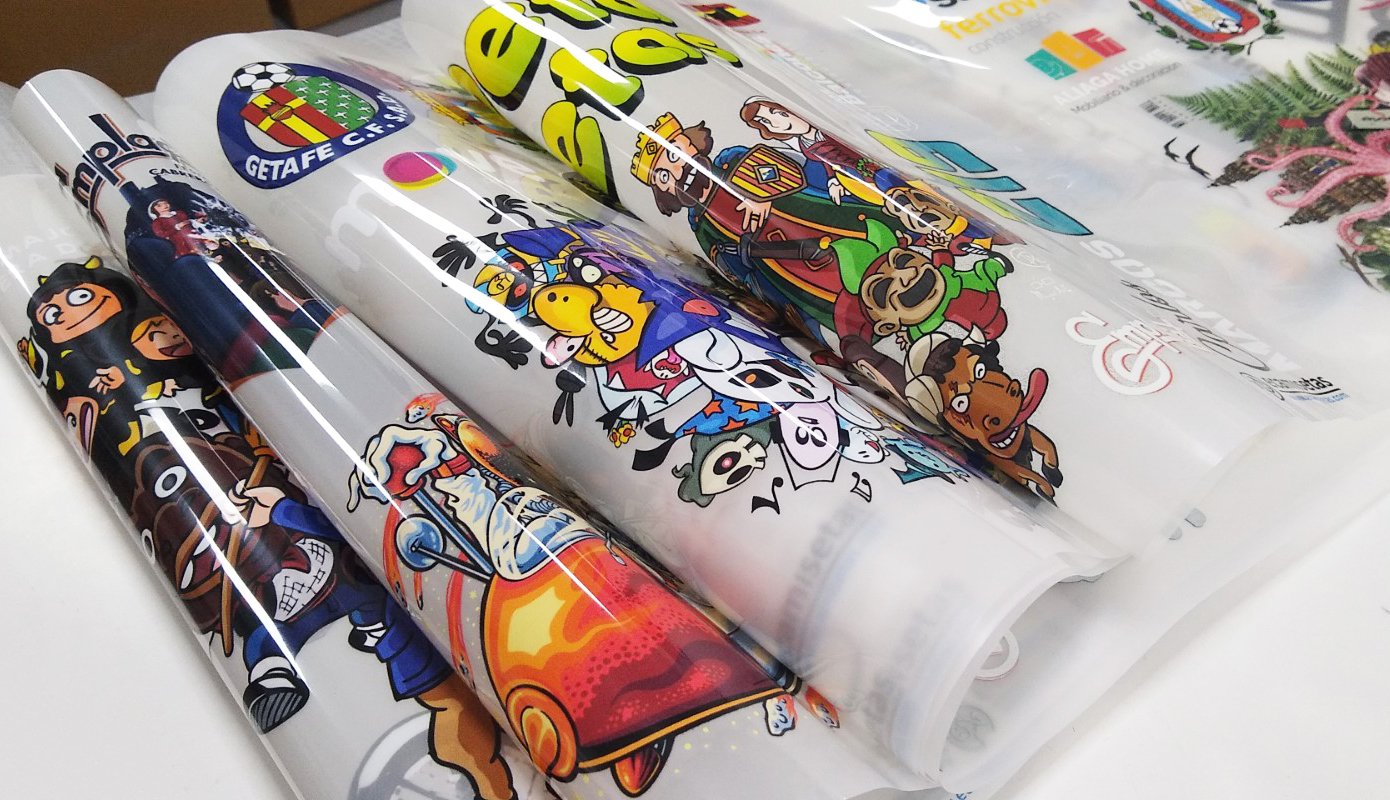 Rolled posters featuring colorful cartoon-style graphics and logos, partially unrolled, resting on a flat surface.