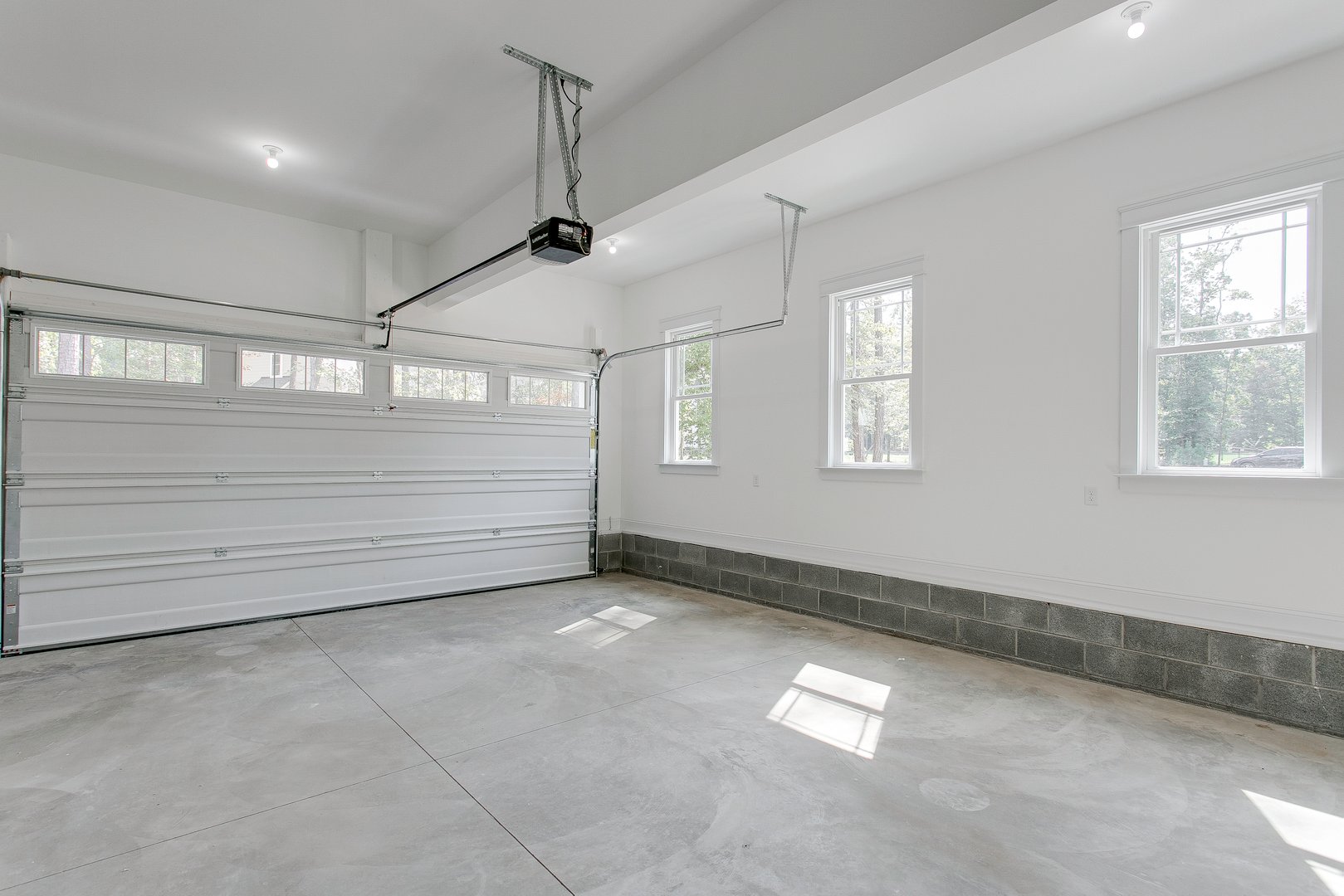 This image depicts a clean, bright garage with dual overhead doors half open, providing an inviting space with ample natural light filtering through the windows.
