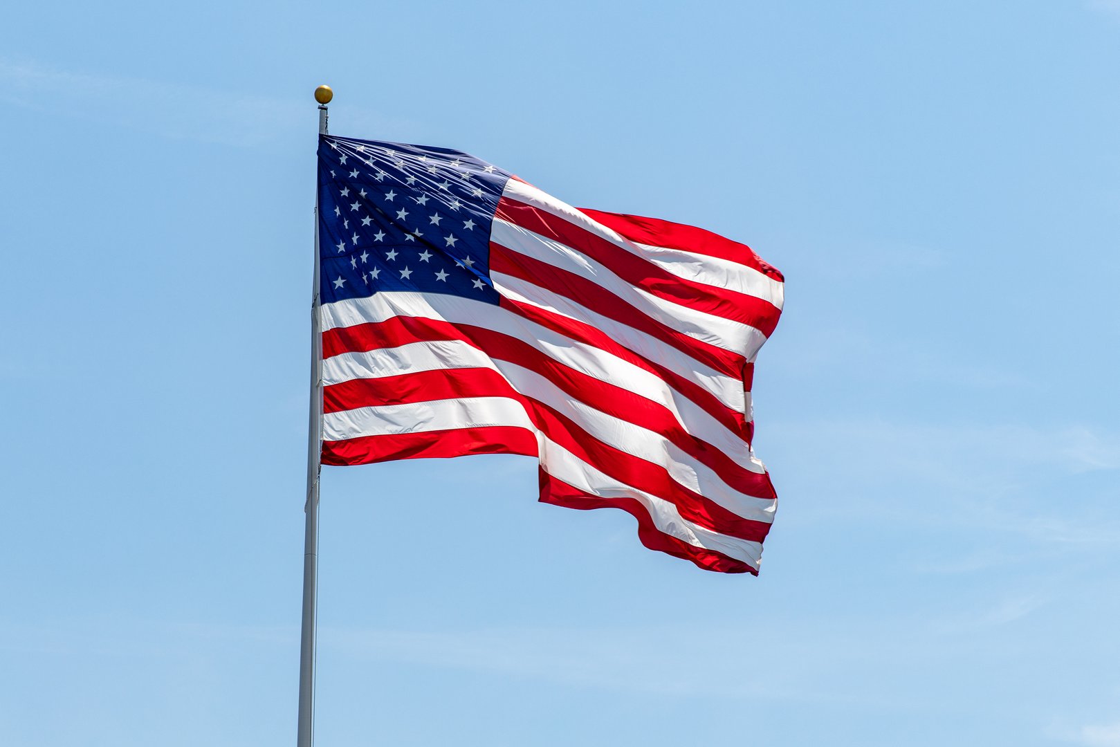 American flag waving on pole with bright vibrant red white and blue colors, negative space