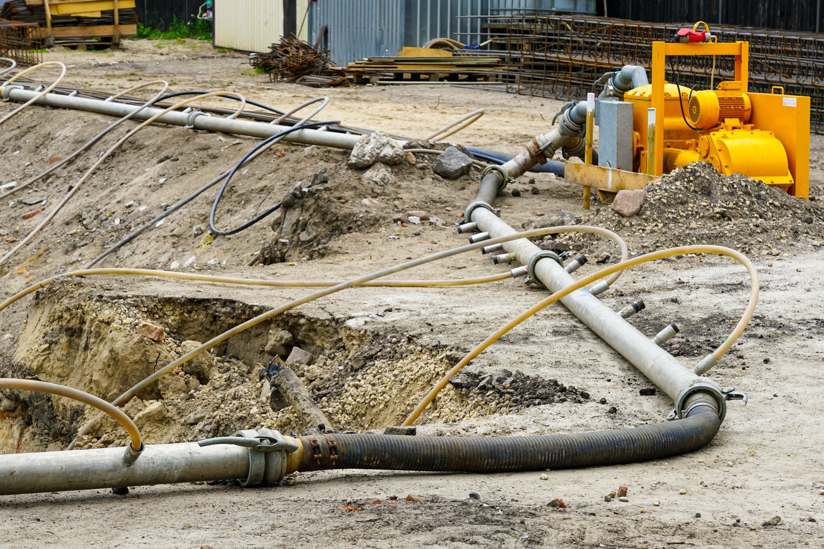 Industrial dewatering pump with pipes and hoses set up at a construction site to manage groundwater, drainage, and foundation stability