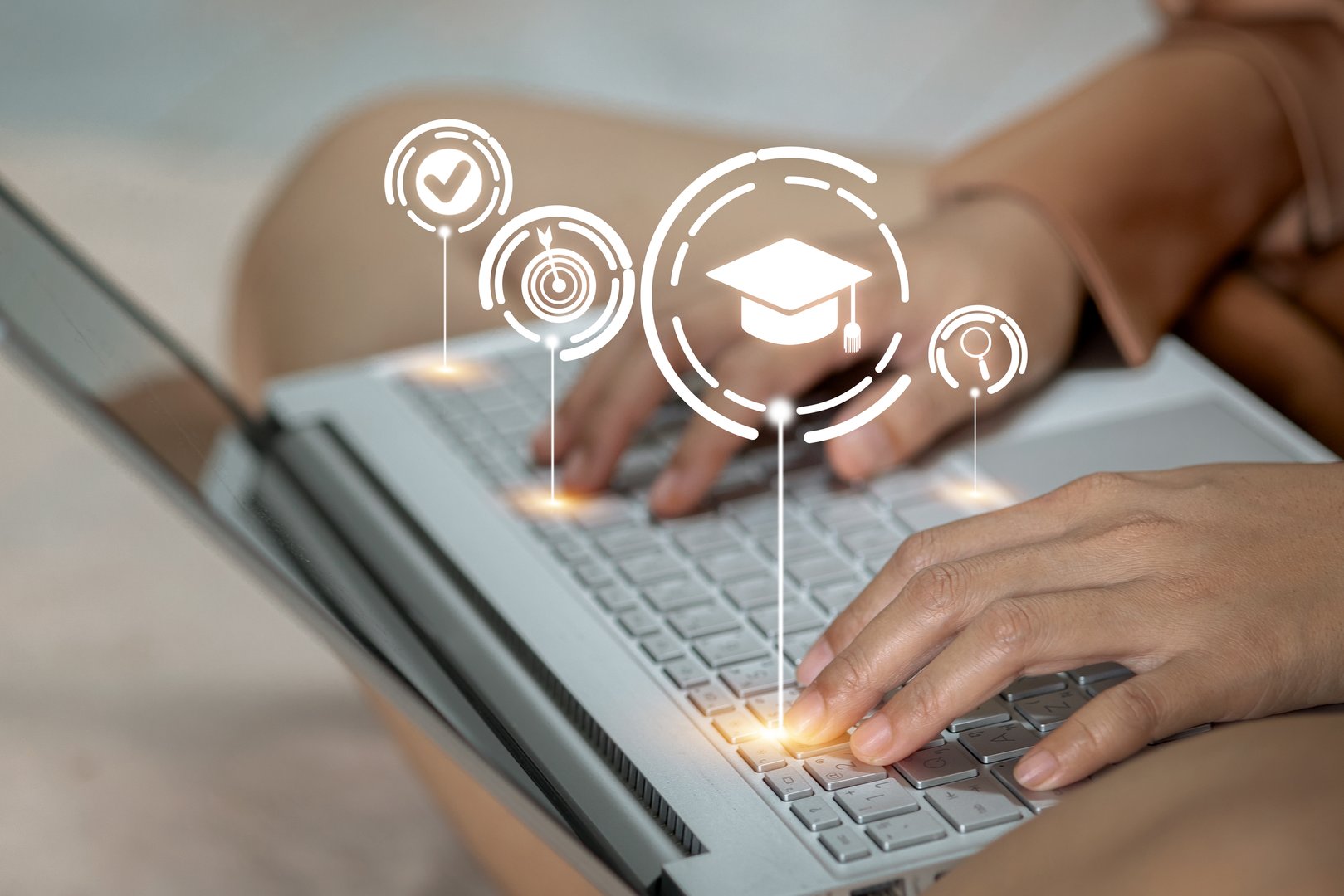 A woman is typing on a laptop with a graduation cap on the screen. Concept of education and achievement