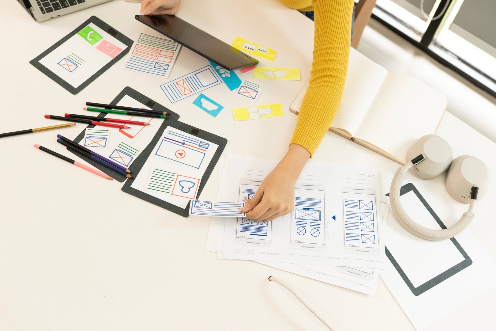 Creative web designer brainstorming app interface and designing digital templates in a modern workspace. UX/UI development process in a professional tech environment.