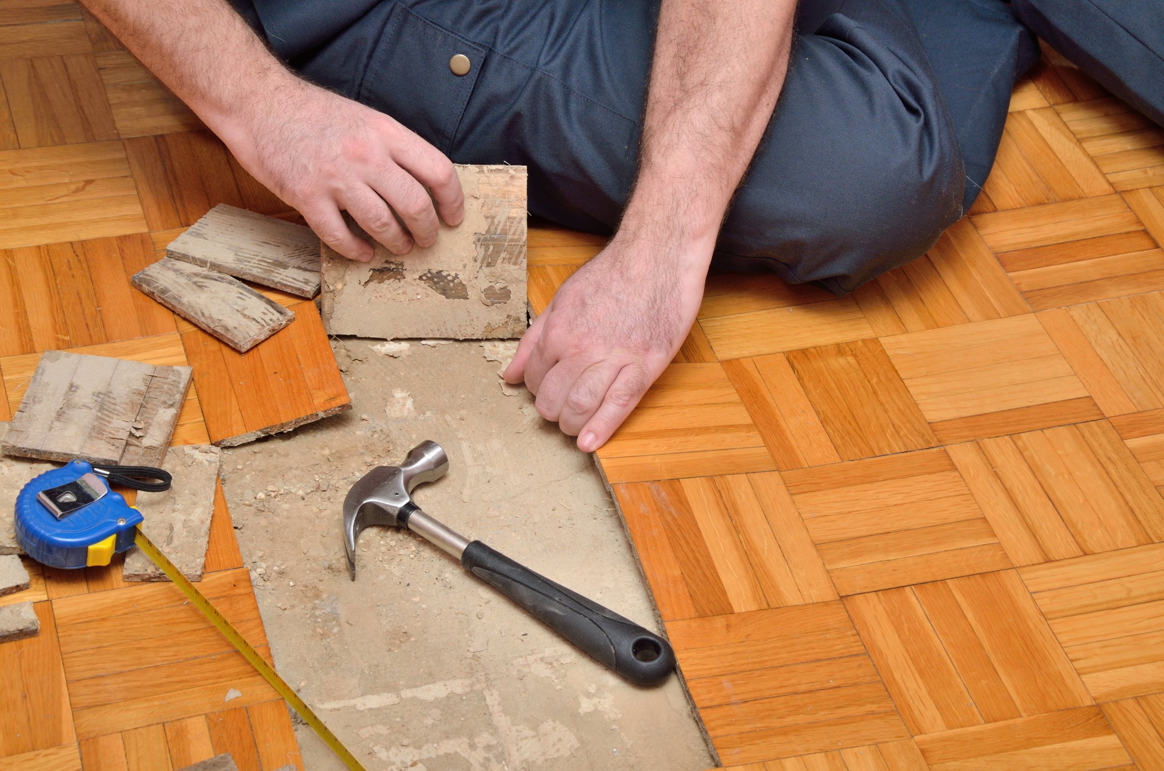 Worker removing pieces of parquet damaged by moisture or water