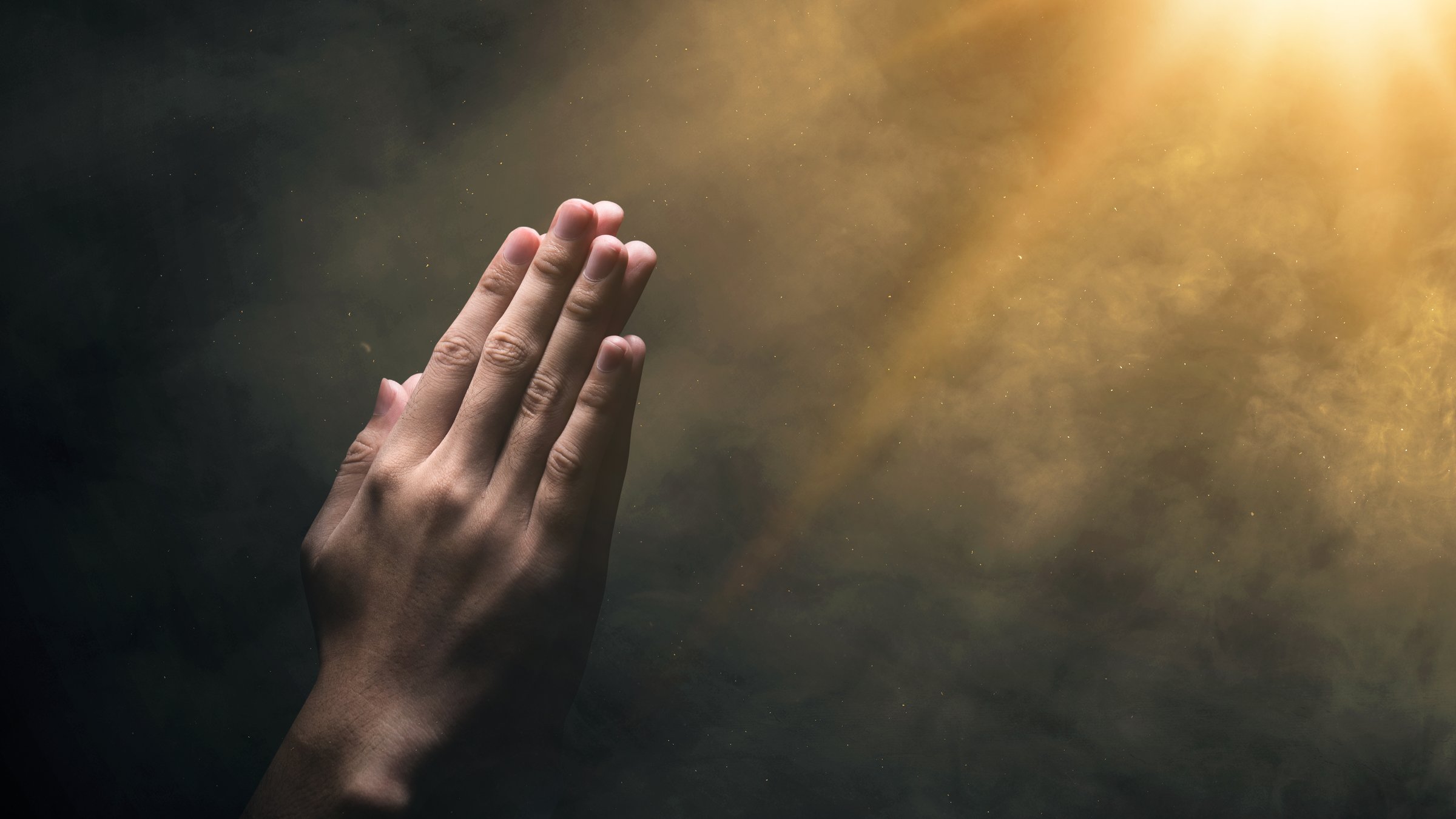 Christian man praying with raised hands on a bright light background. Christian concept