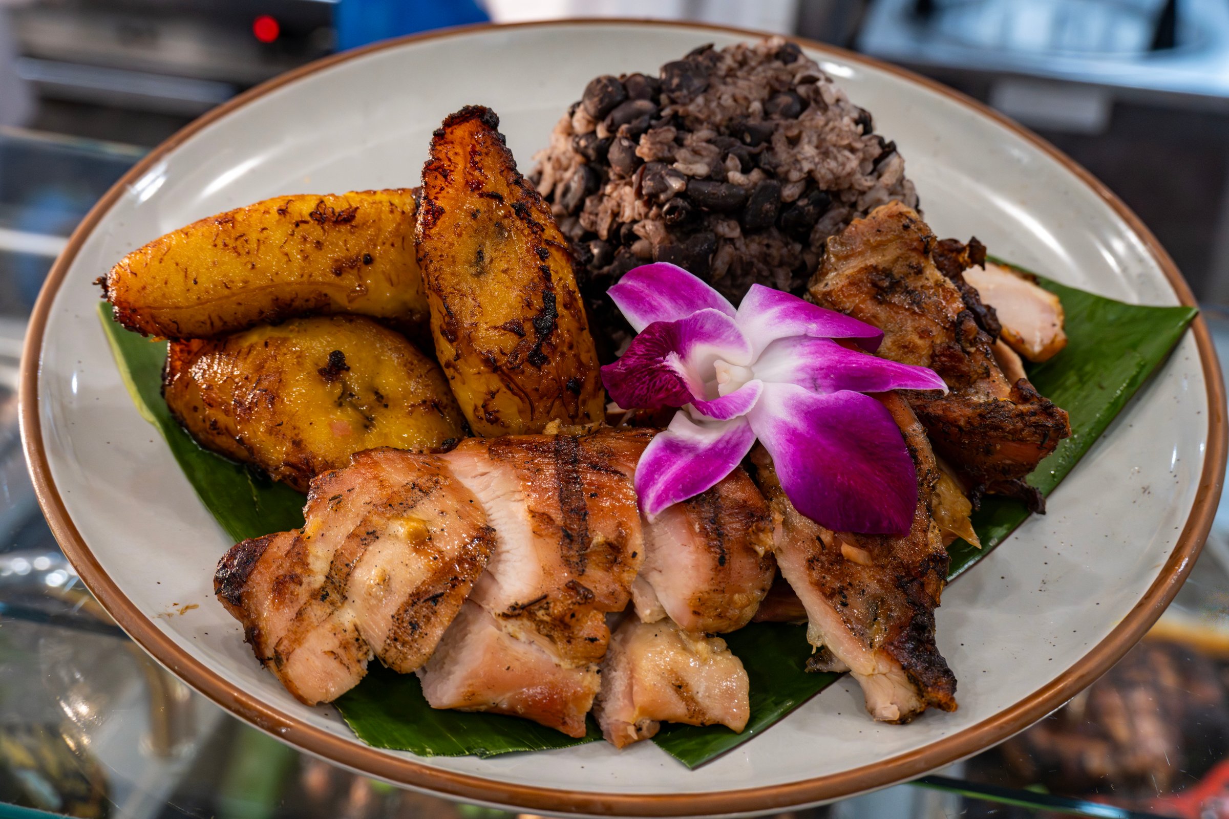 A plate of jerk chicken, roasted plantains and black beans and rice
