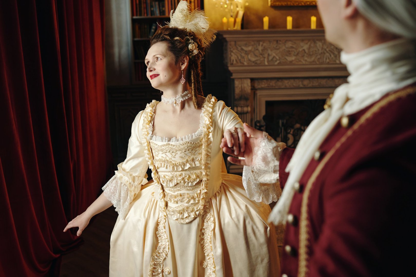 Caucasian young adult woman wearing elaborate Baroque style dress holding hand of Caucasian middle aged man in historical costume standing in ornate Renaissance interior