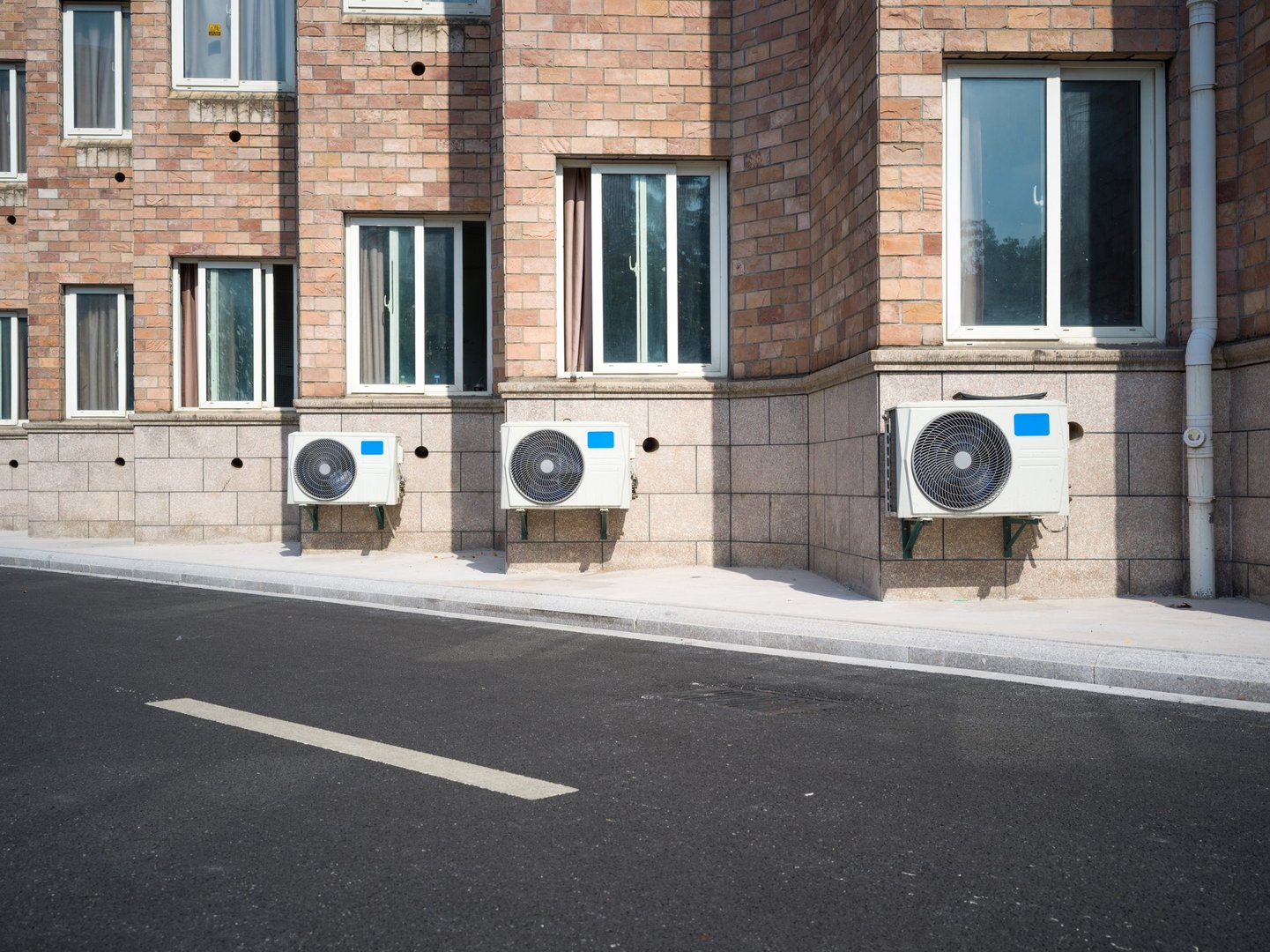 AC unit attached to brick building with white-framed windows