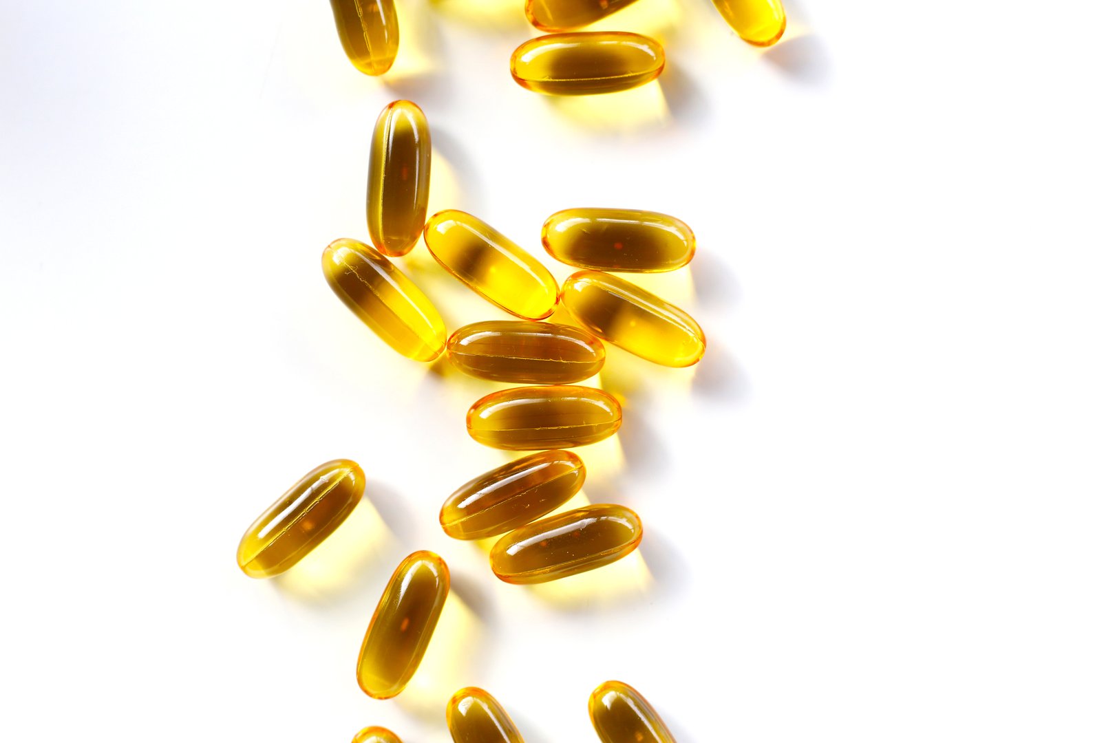 Golden fish oil capsules on white background.
