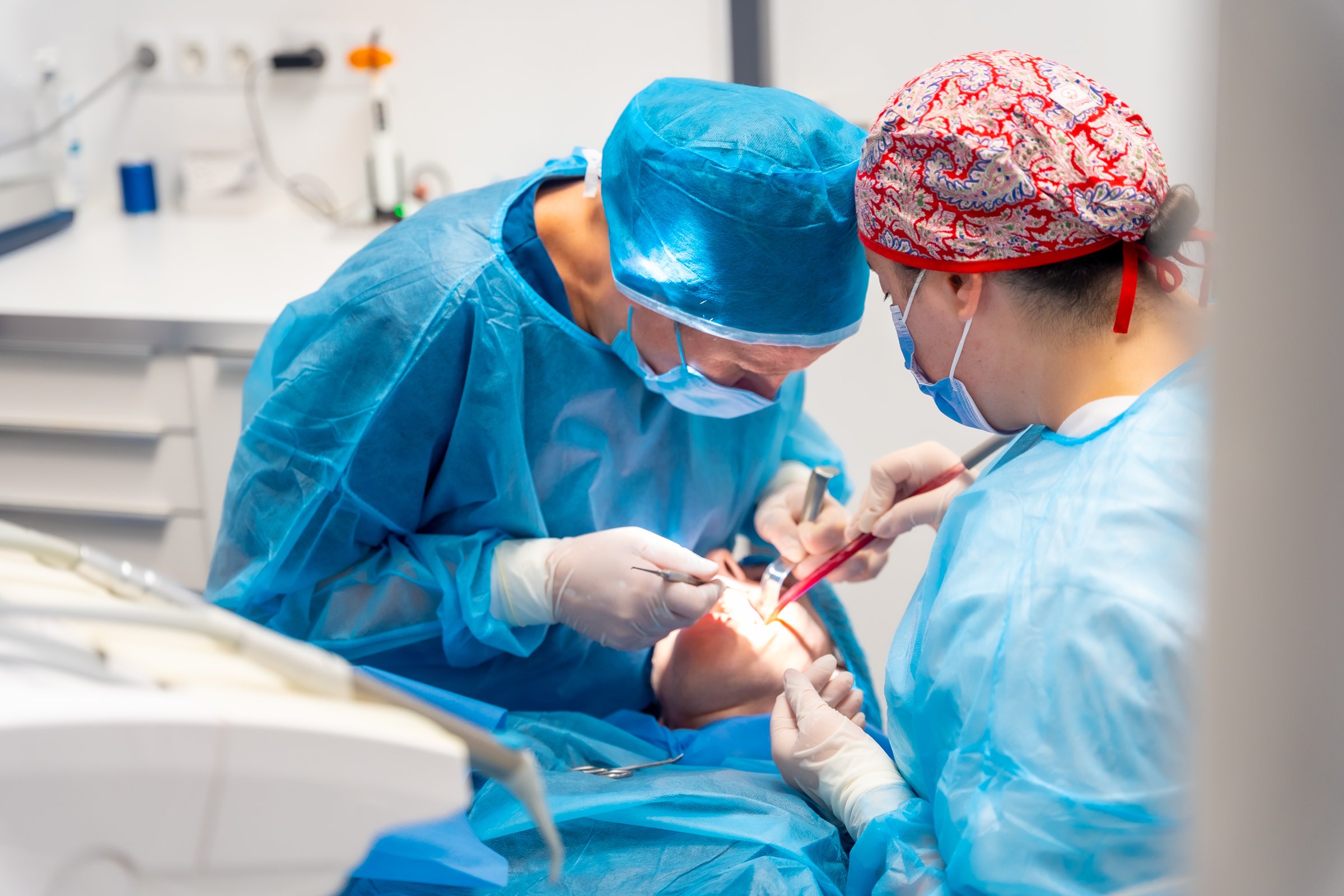 Dental clinic, dentist doctor and the assistant performing an oral operation to a client