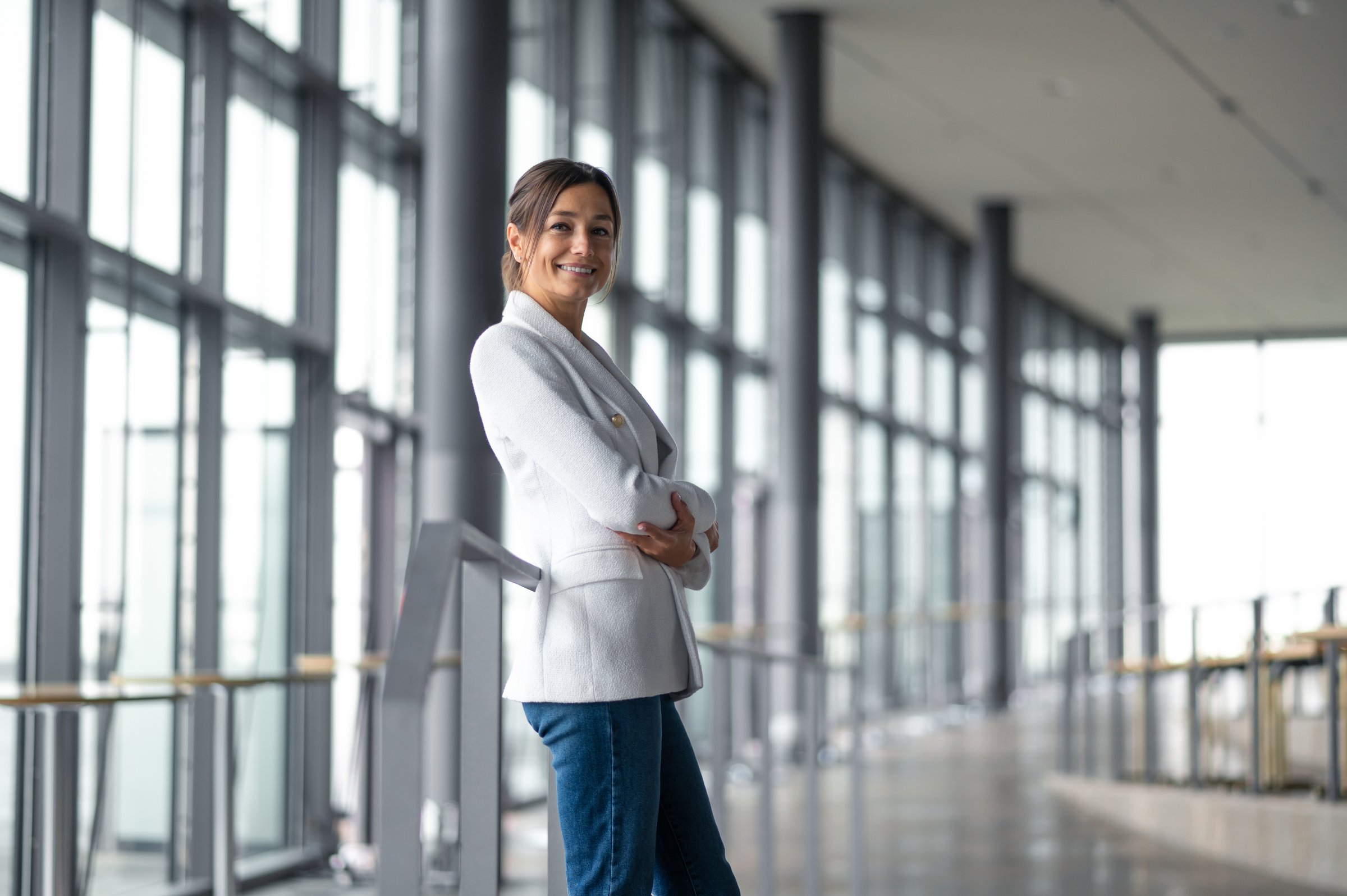 Confident business lady. Confident elegant woman in white jacket standing in the premises with big windows
