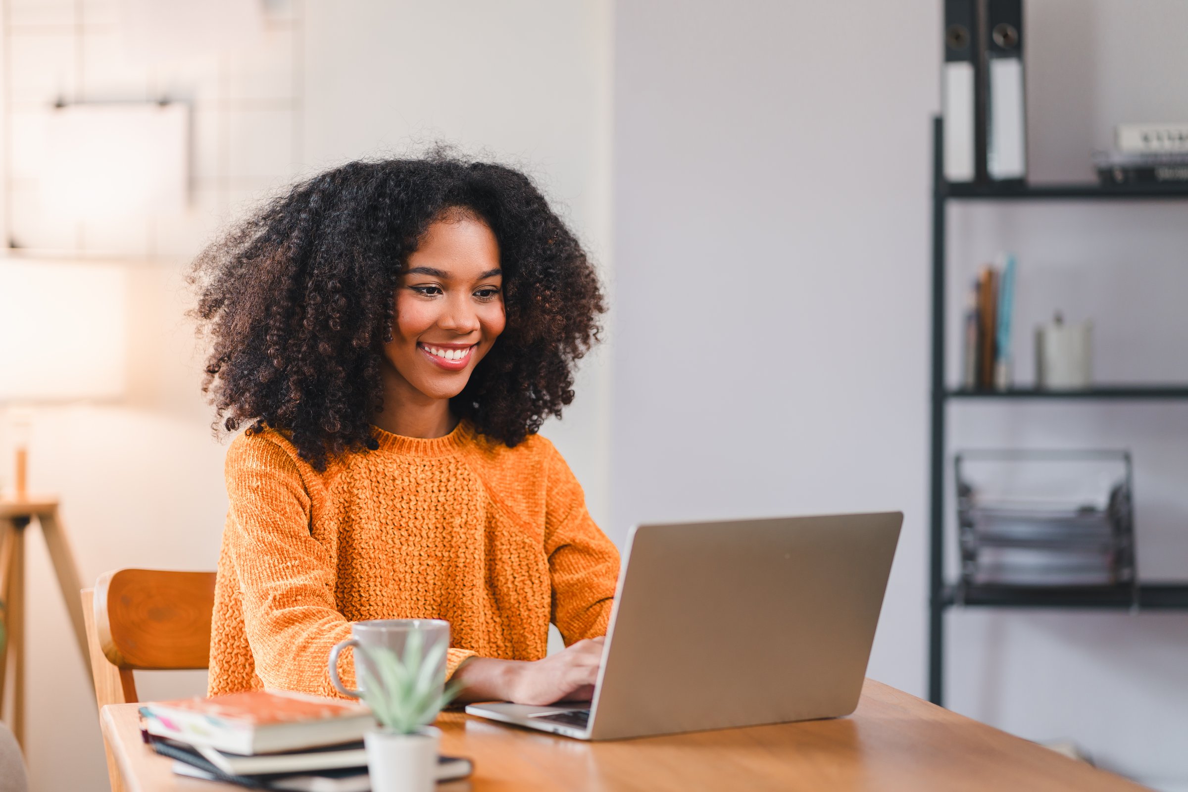 Smiling African woman using laptop while working