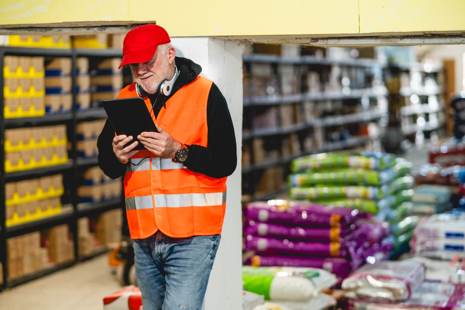 An older worker in a pet food warehouse prepares deliveries of goods for pet stores