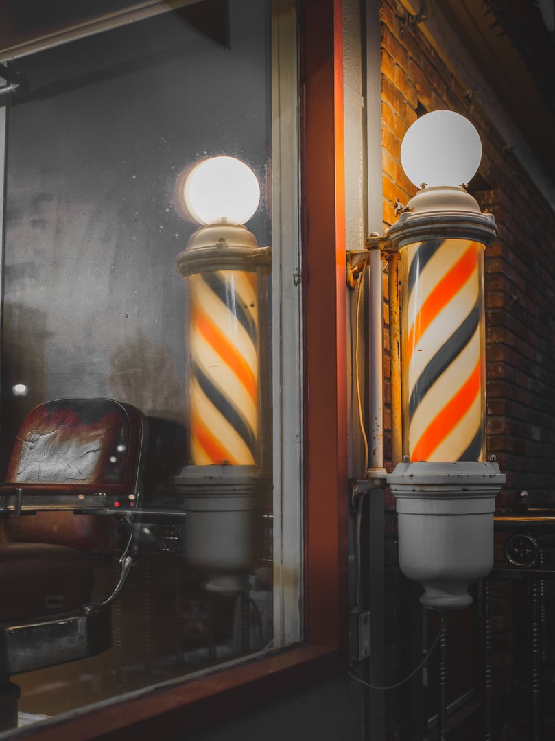 An old fashioned barber shop and striped barber pole There is something about a barber shop atmosphere in the evening that is set in tradition.