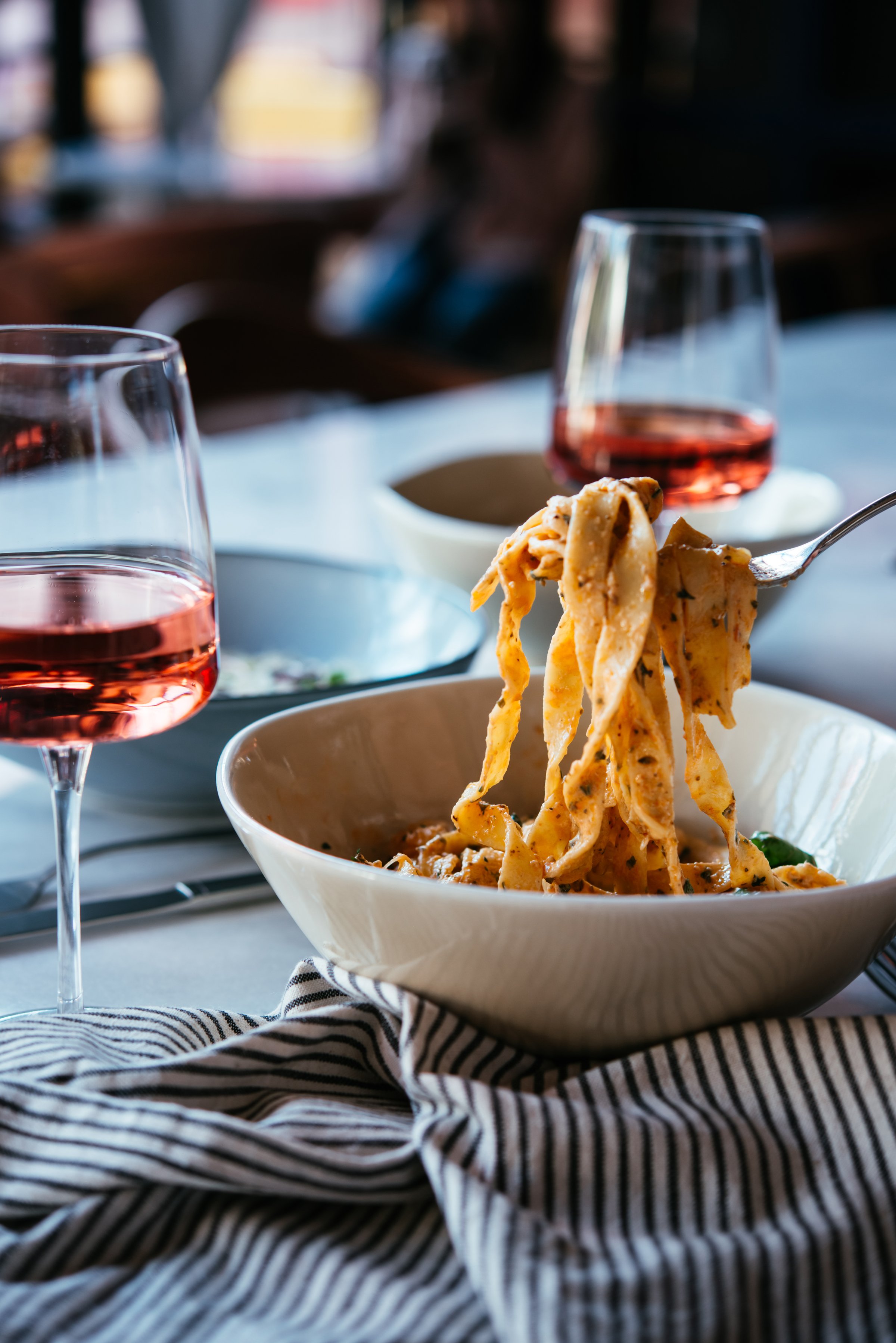 Having a pasta dinner with rose wine at home or in a restaurant.