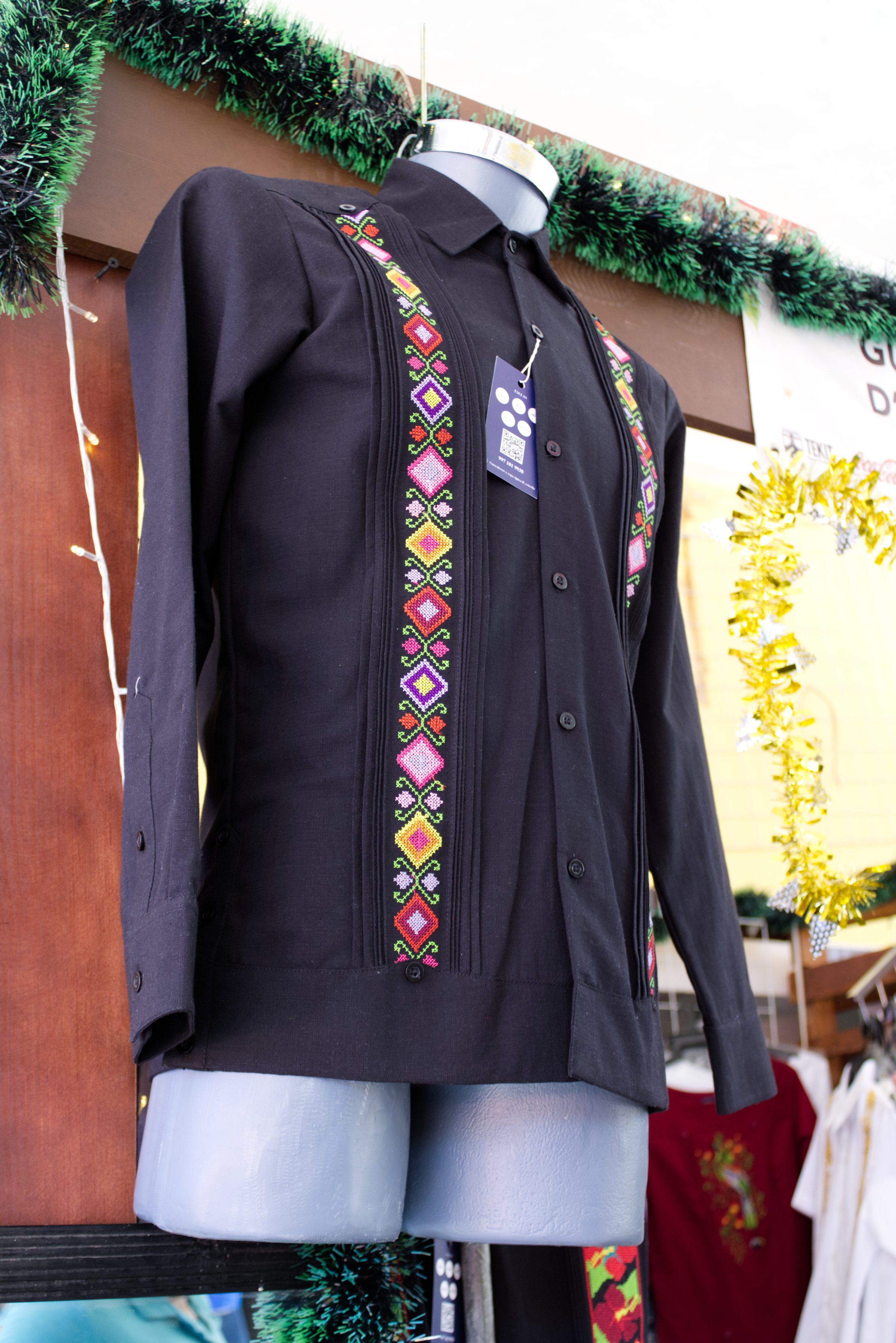 Guayabera stall in Tekit, Yucatan December 28, 2022. Mexico. Yucatecan style shirt, hanging on a hook for display. Mexican shirt, it's black and it has stripes. Clothes shop
