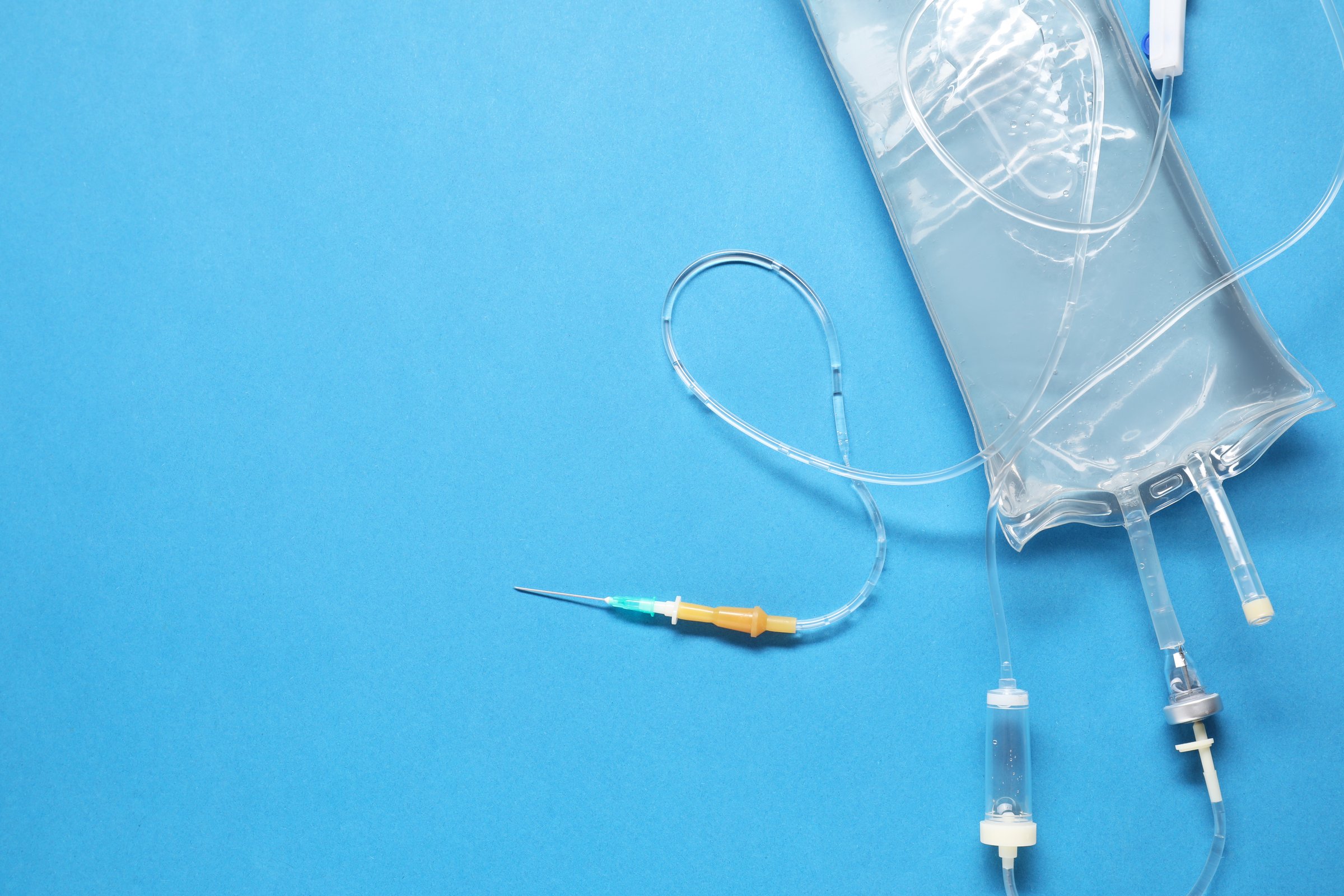 IV infusion set on light blue background, top view. Space for text