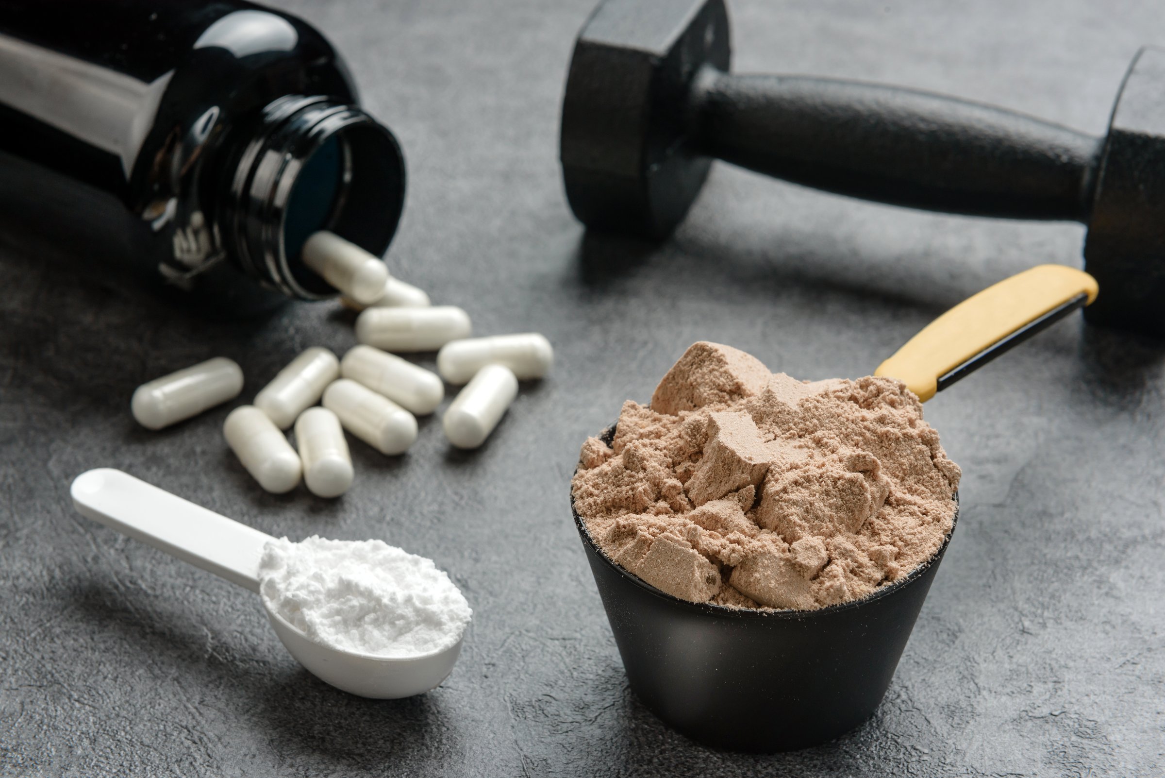 Chocolate flavored protein, creatine and amino acid capsules close-up. The concept of sports supplements.