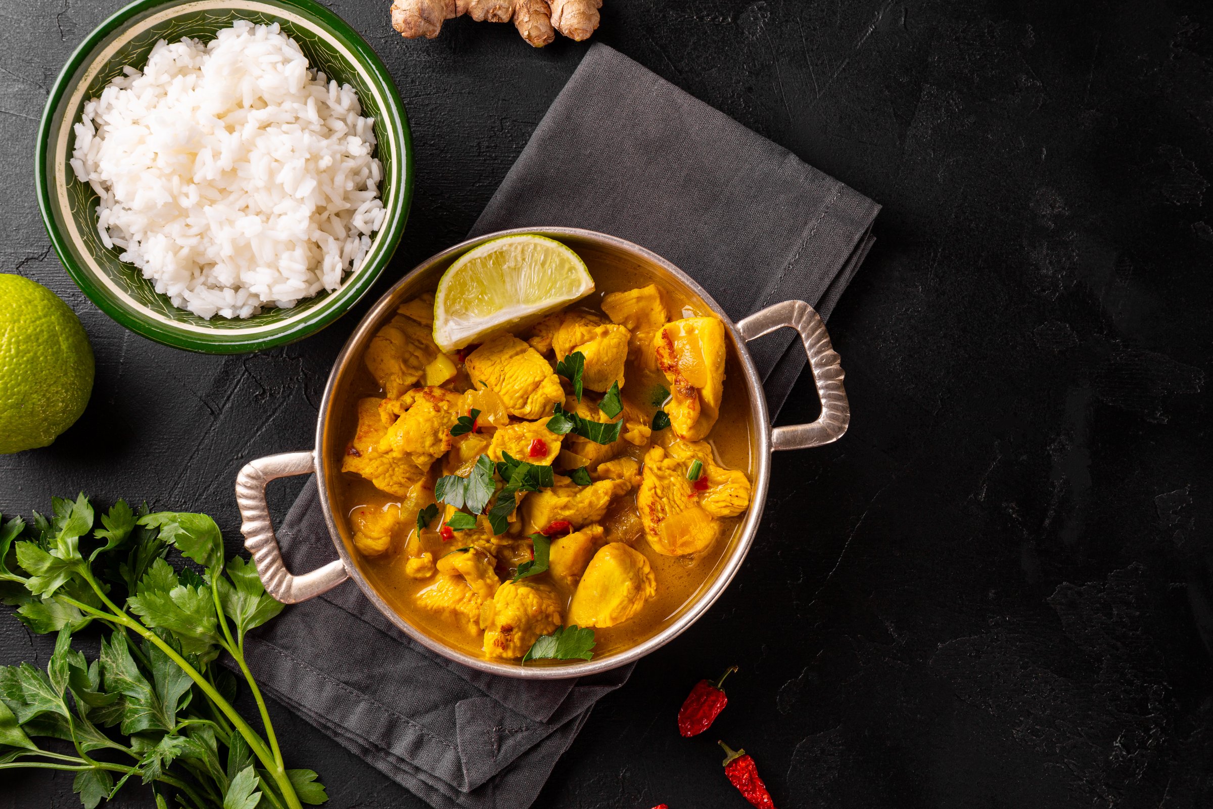 Chicken in curry sauce and rice on black background, Indian food top view. High quality photo