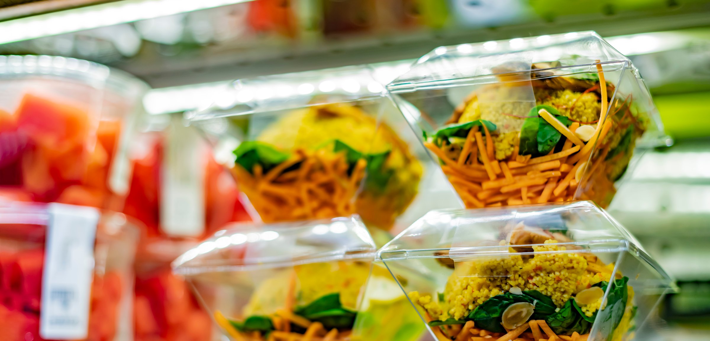 Pre-packaged ready to eat meals and fruit salads displayed in a commercial refrigerator