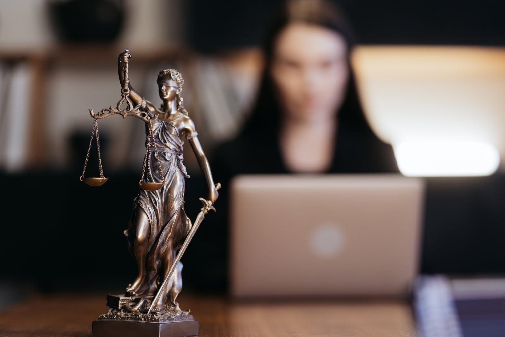 Lawyer's office. Statue of Justice with scales and a lawyer working on a laptop. Concept law, legal advice, and justice.
