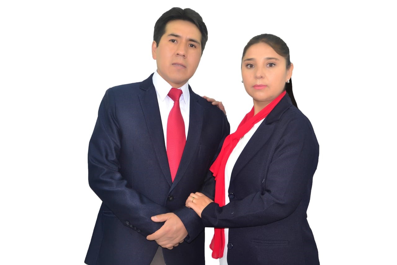 A man and woman in formal attire with red ties pose against a plain white background.