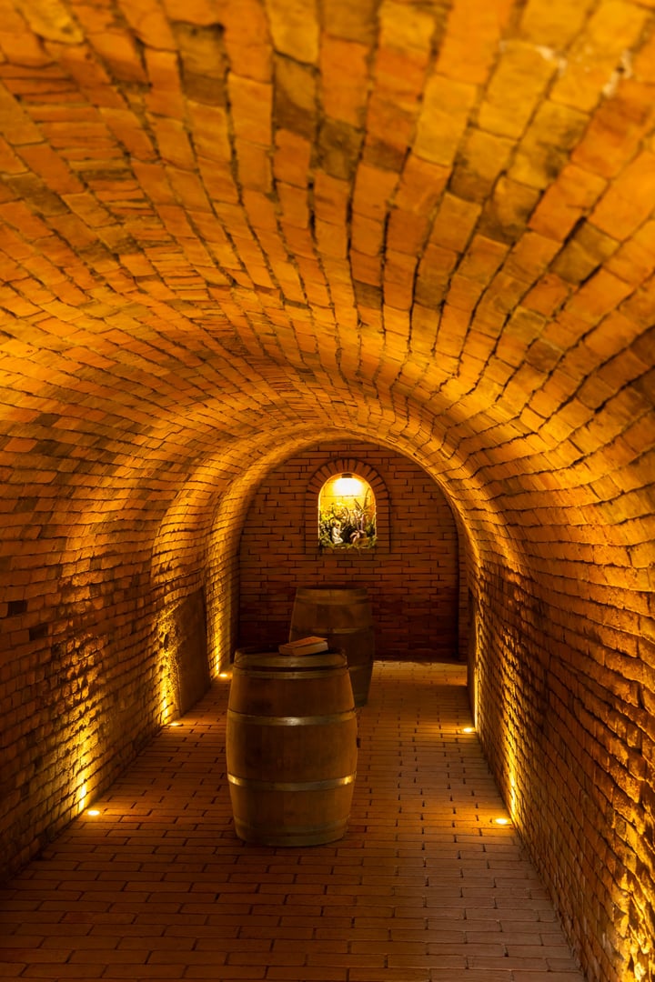 Wooden barrels aging in a traditional brick wine cellar, showcasing the winemaking process in Hadres, Lower Austria