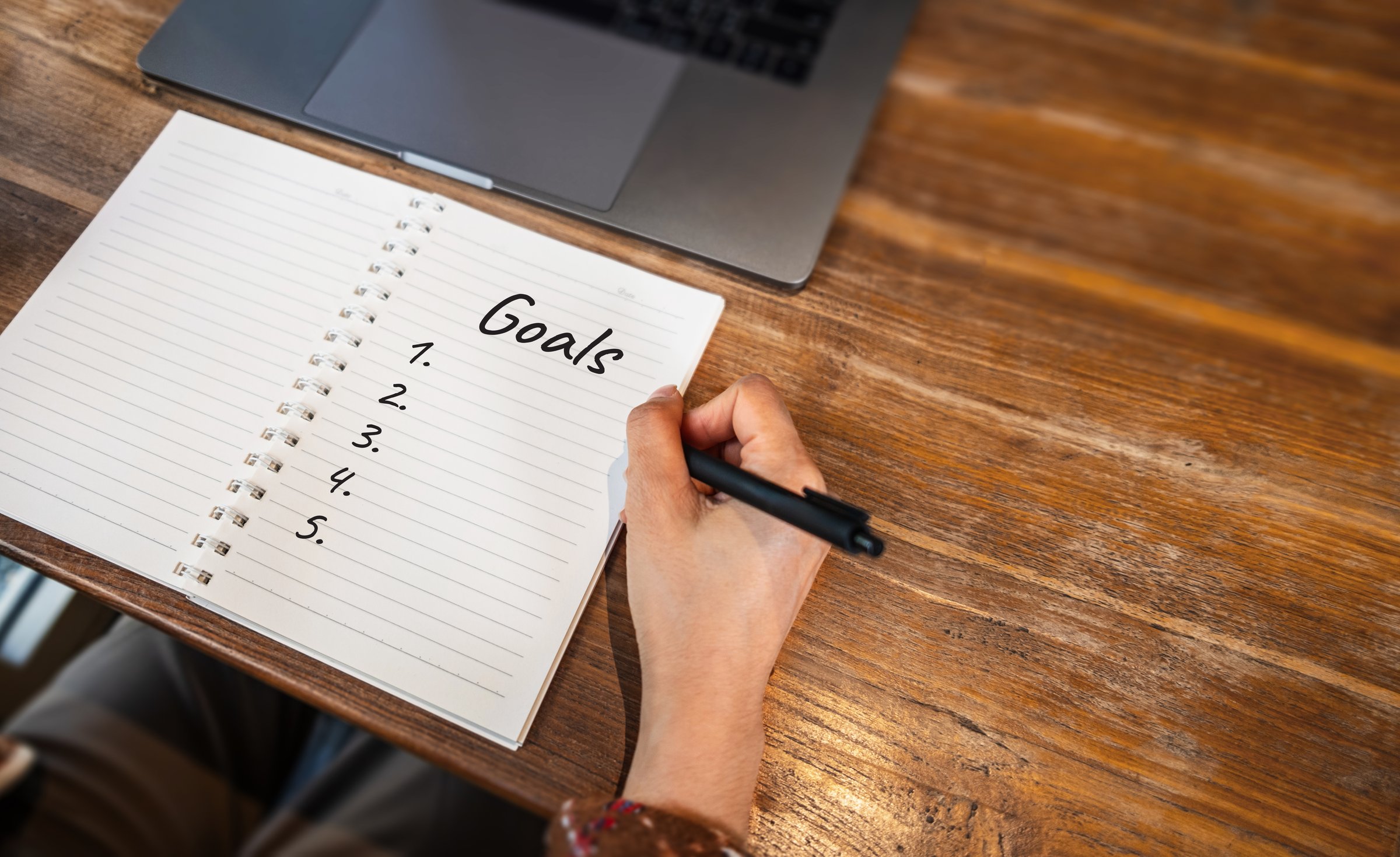 Close-up of a hand writing the word goals 2026 in a notebook. New year planning, goal setting and motivation concept