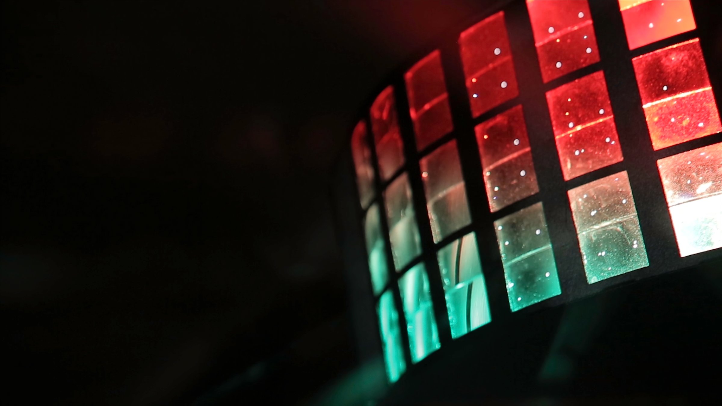 Close-up of a colorful LED display with red and green squares, glowing against a dark background.