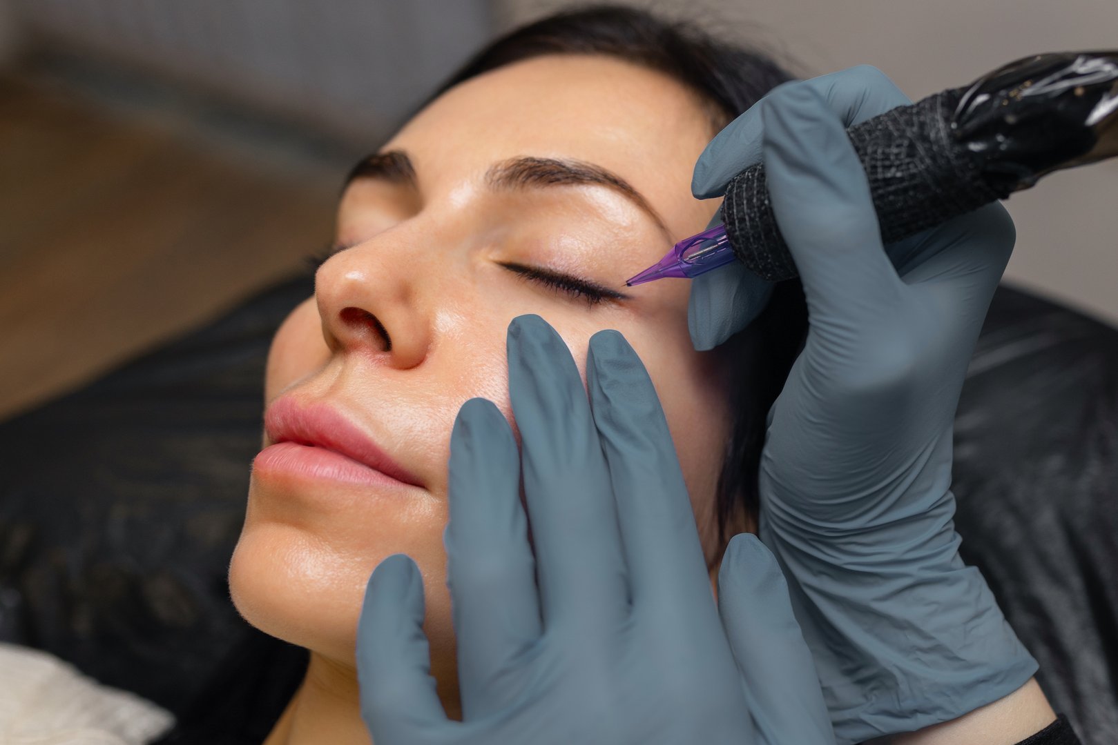 Close up of a cosmetologist performing eyelid permanent makeup, precision eyeliner tattoo procedure with sterile tools, enhancing lash line and eye beauty in a professional studio