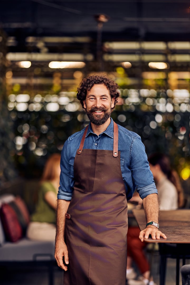 Friendly male bartender in casual attire at an outdoor bistro offering service
