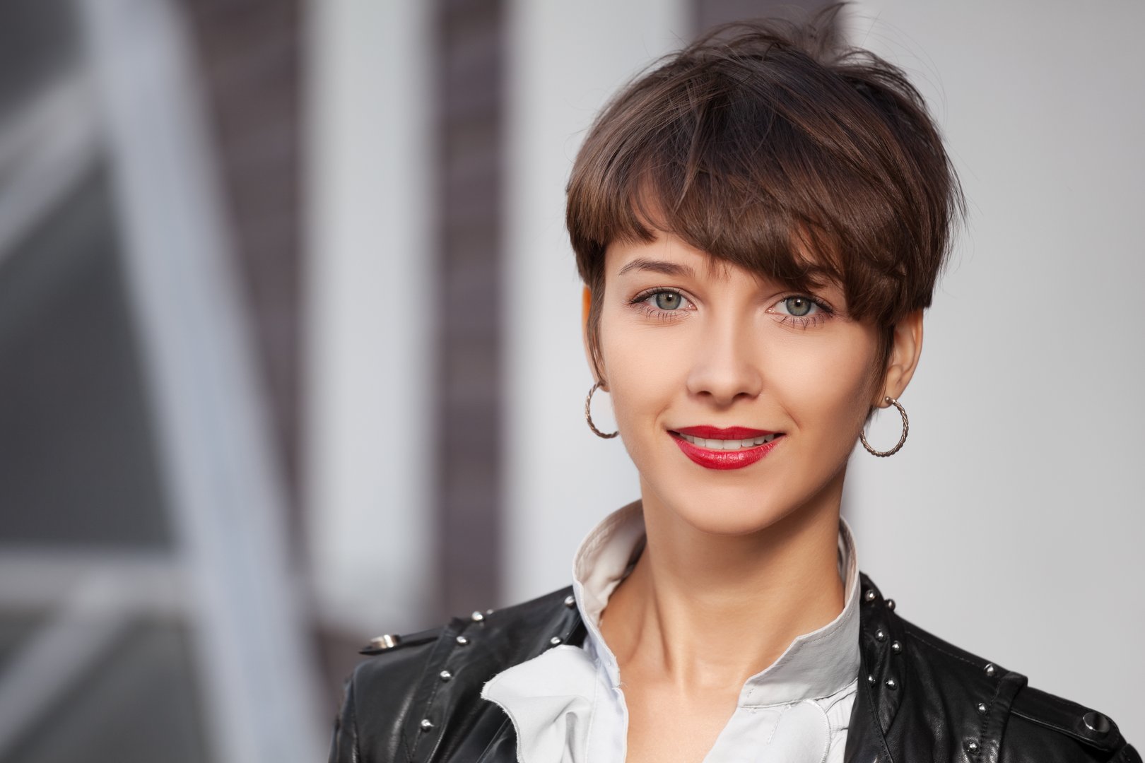 Happy young fashion woman in leather jacket walking in city street