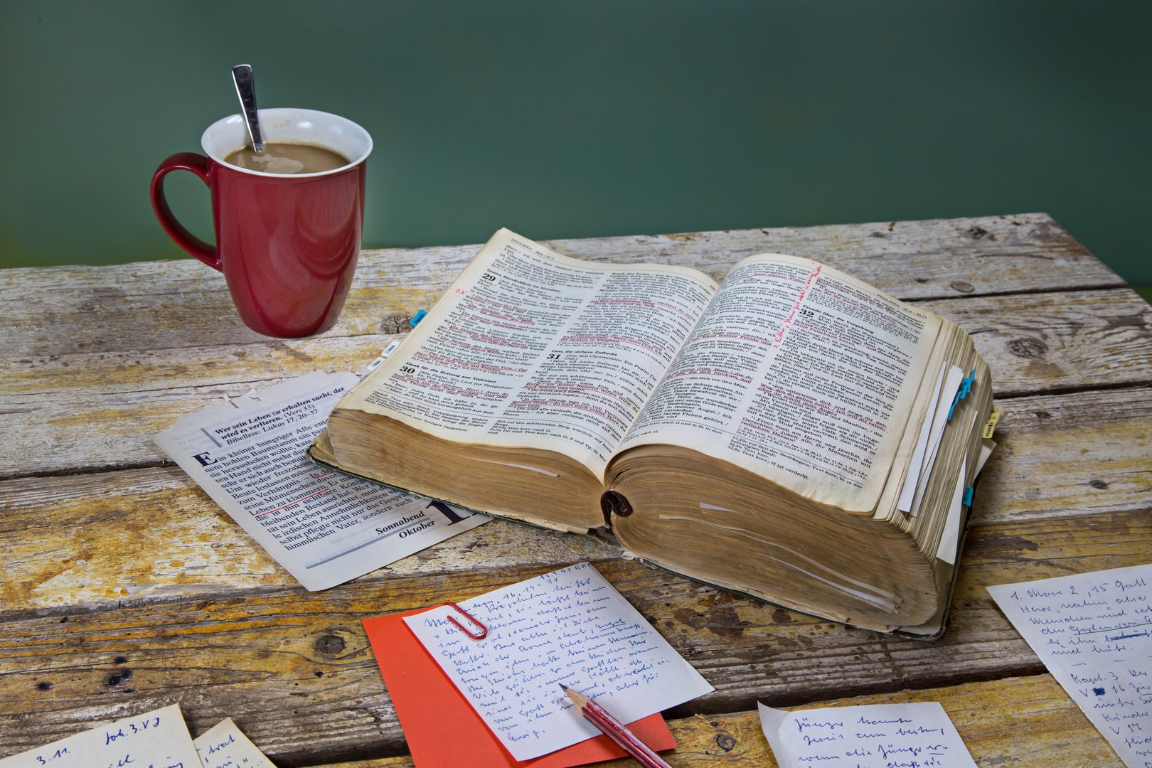 On a wooden table a bible, cup of coffee, pen, some notes