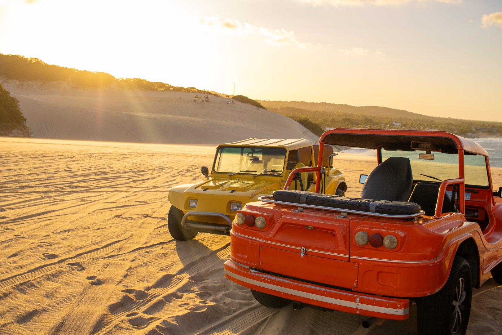 Buggies on the dunes during a sunset on a sunny day.