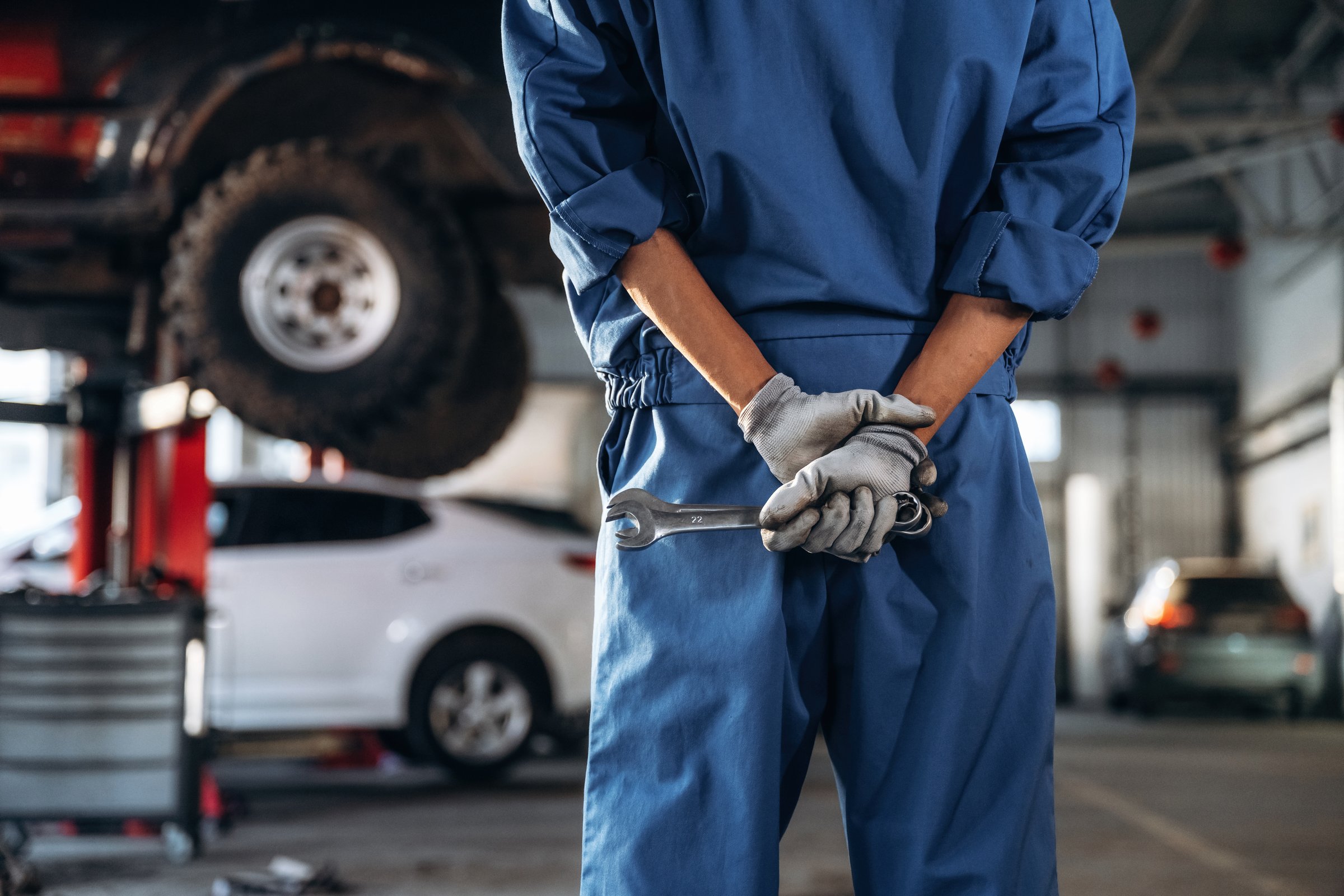 Tools in hands. Male mechanic is with car in garage.