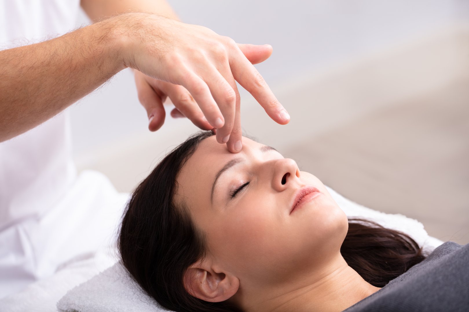 Close-up Of A Young Woman Receiving Reiki Treatment By Therapist