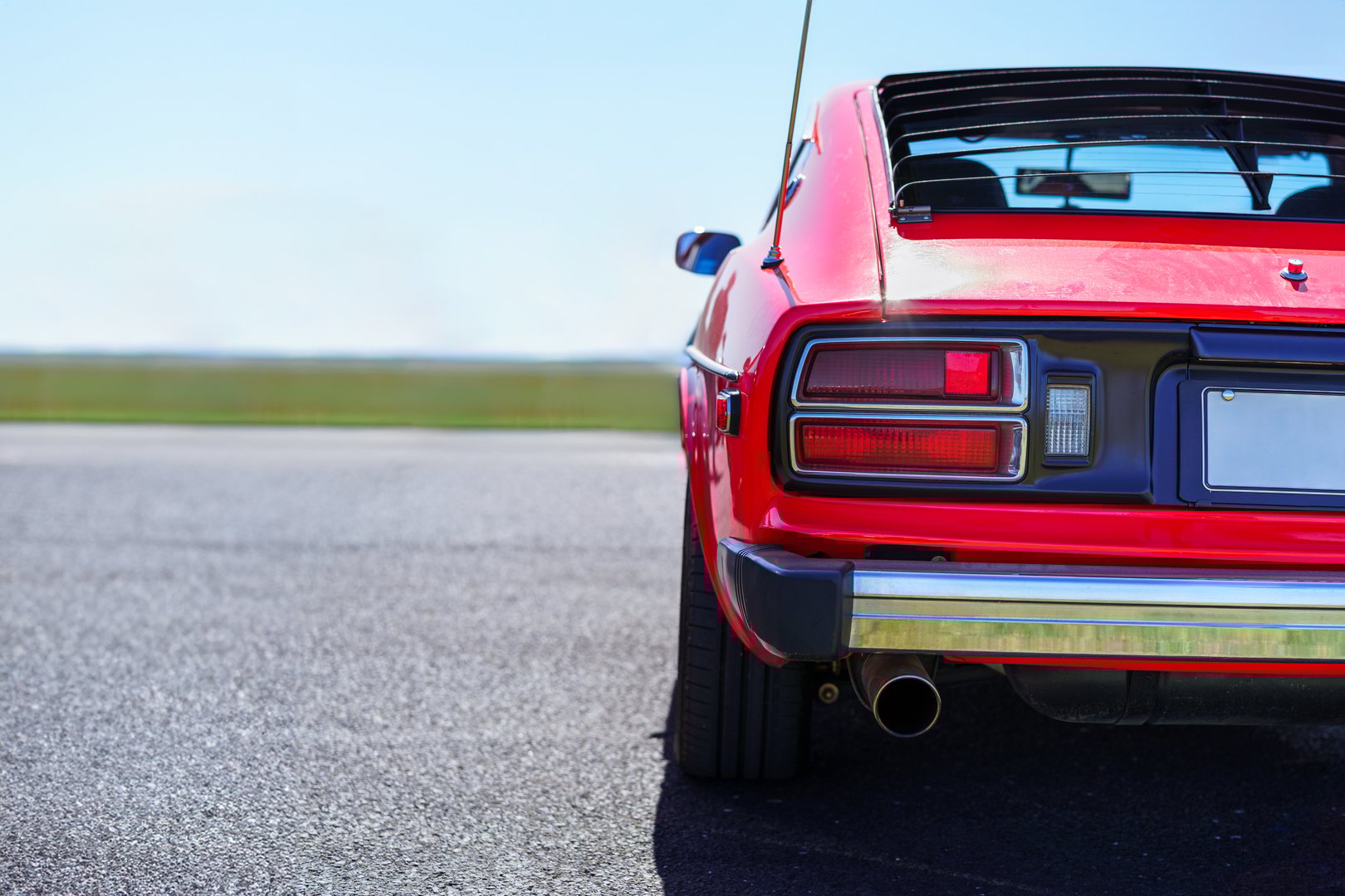 Red vintage sports car rear view parked outdoors in sunlight