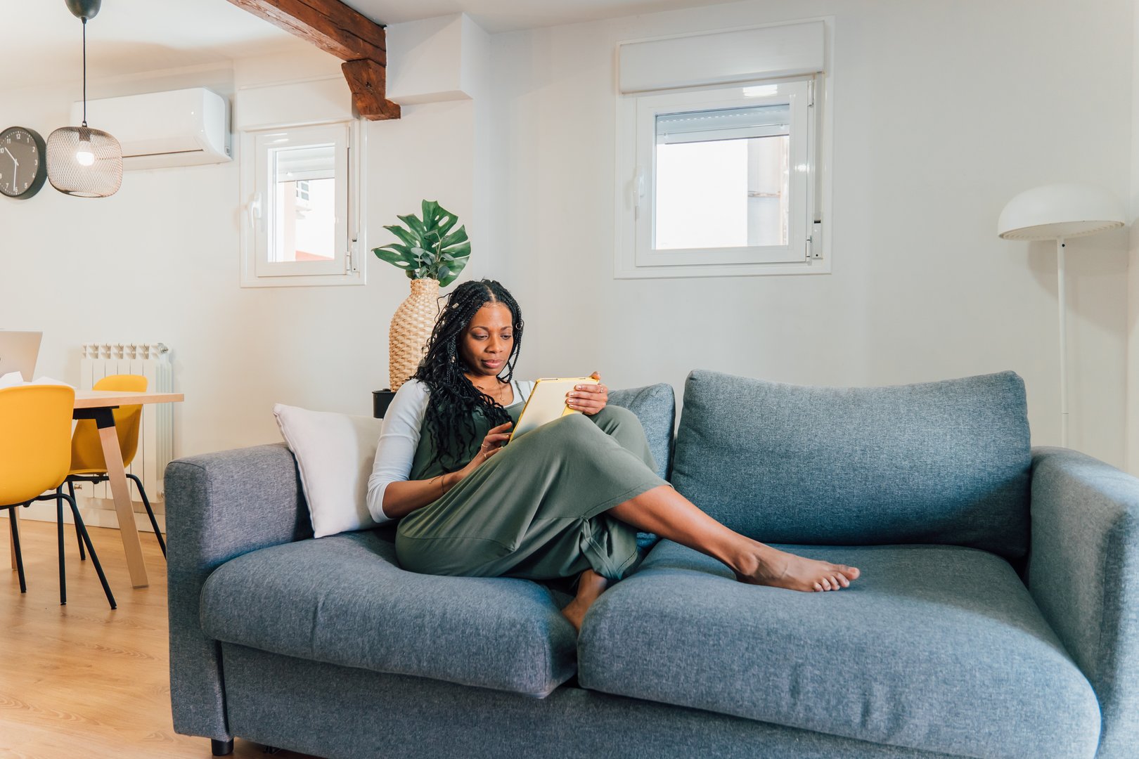 Serene woman enjoying a peaceful moment at home, comfortably reading a book on her sofa in a stylish, modern apartment