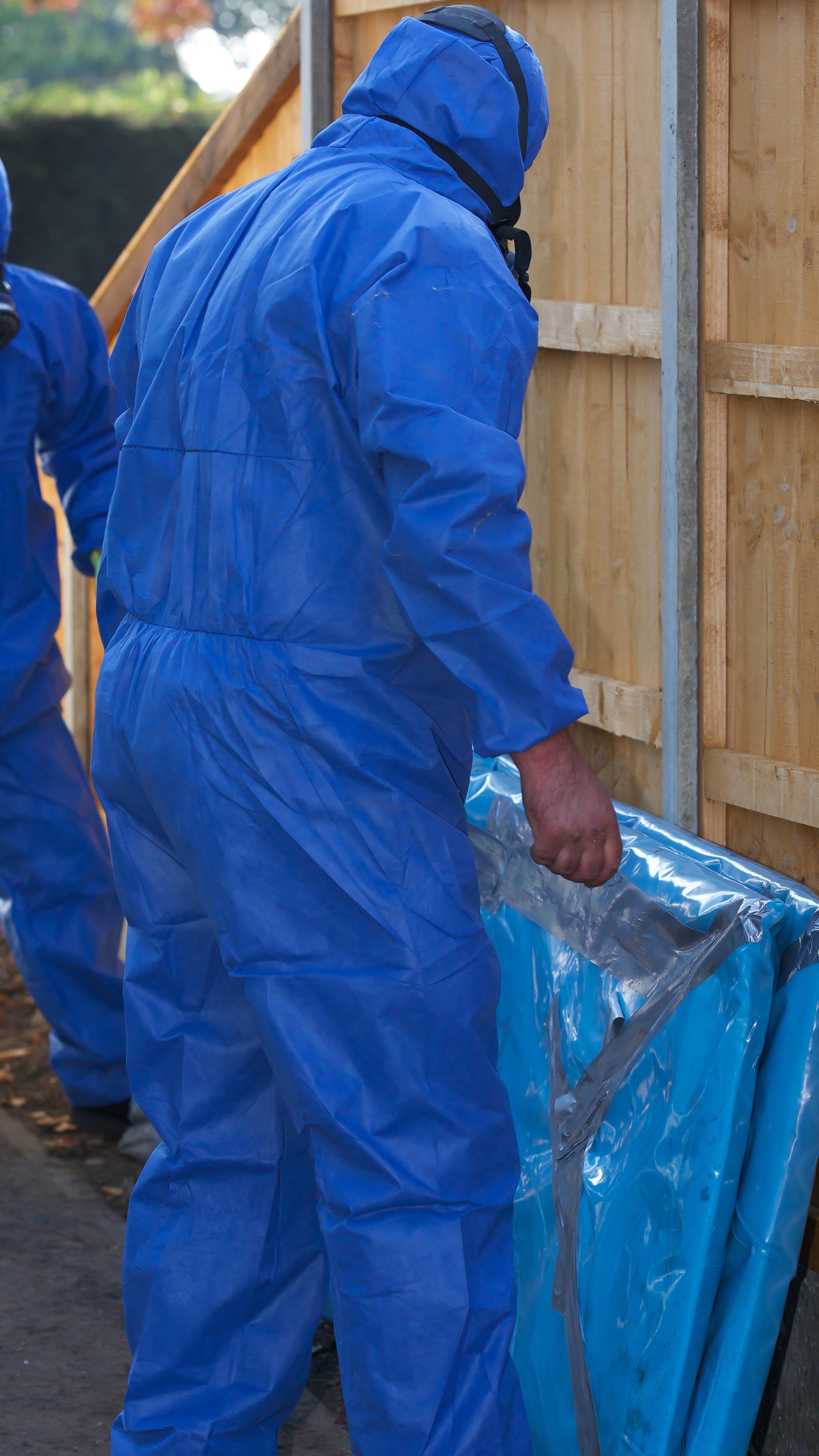 Grey asbestos being removed from a residental property by experts - asbestos sheets being encapsulated in plastic before transportation