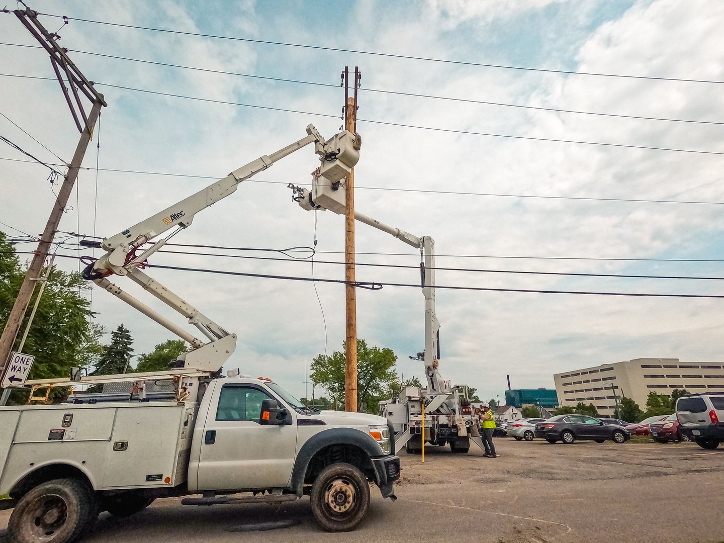 Springfield, Illinois, USA : May 9, 2024 Lineman crews work on power lines high in the sky. An elevated hydraulic bucket lifts the workers up to the power line. City environment.