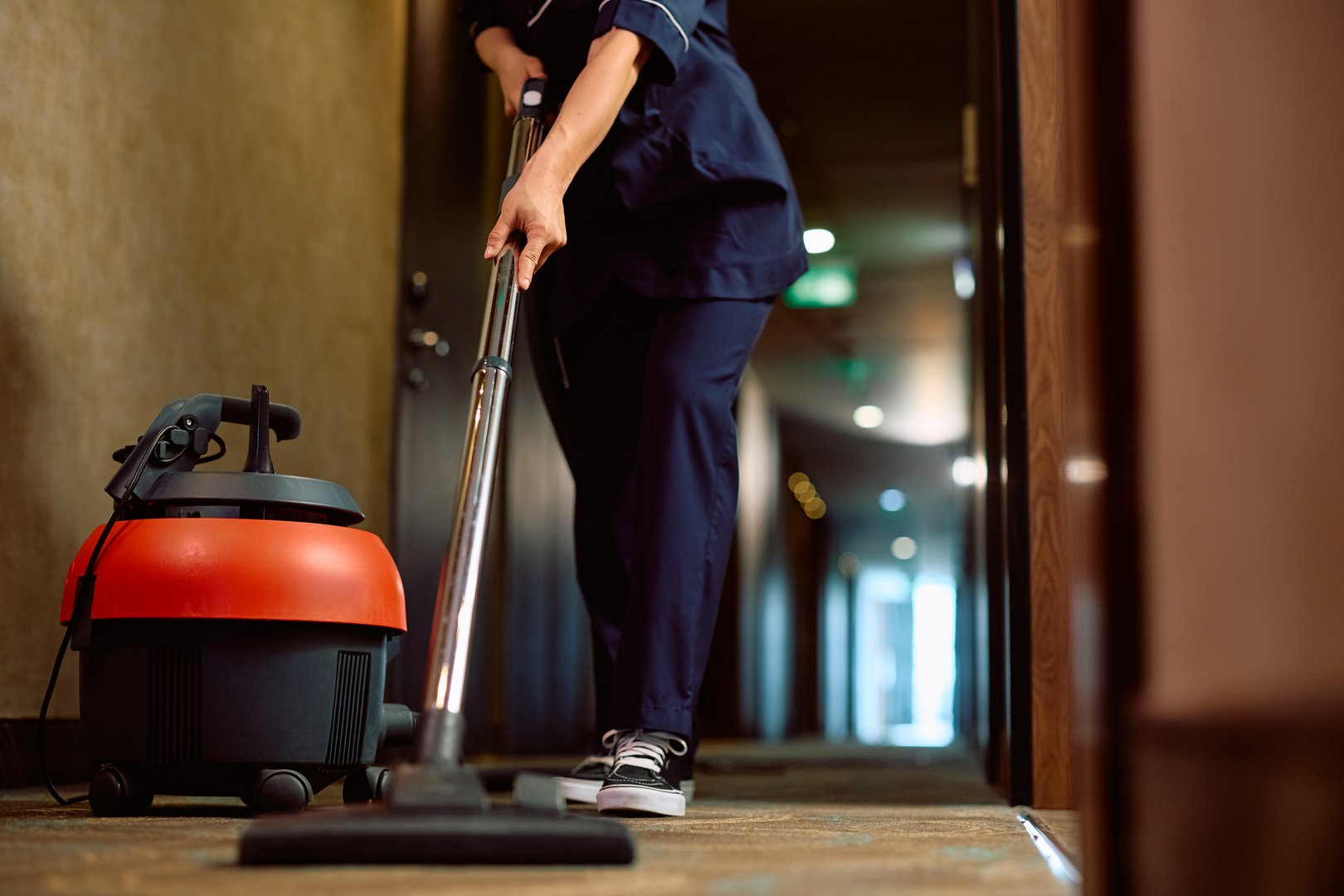 Close up of hotel maid vacuuming the hallway. Copy space.