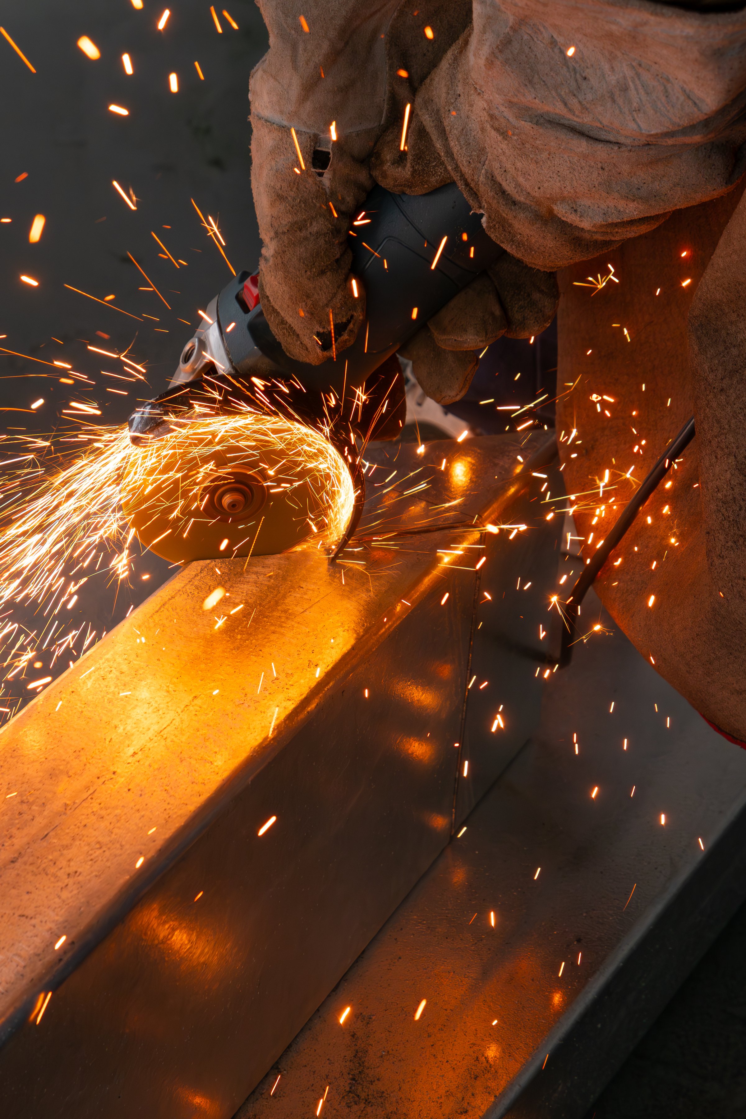 skilled worker cutting an iron pipe with a grinder at vertical composition