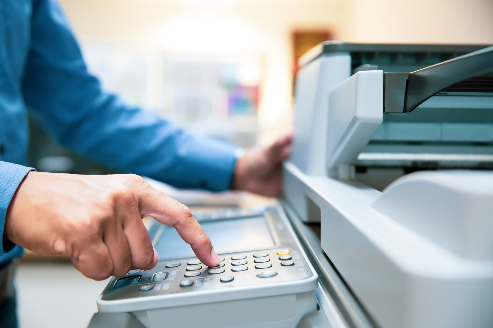 Businessmen press button on the panel for using photocopier or printer for printout and scanning document paper at office.