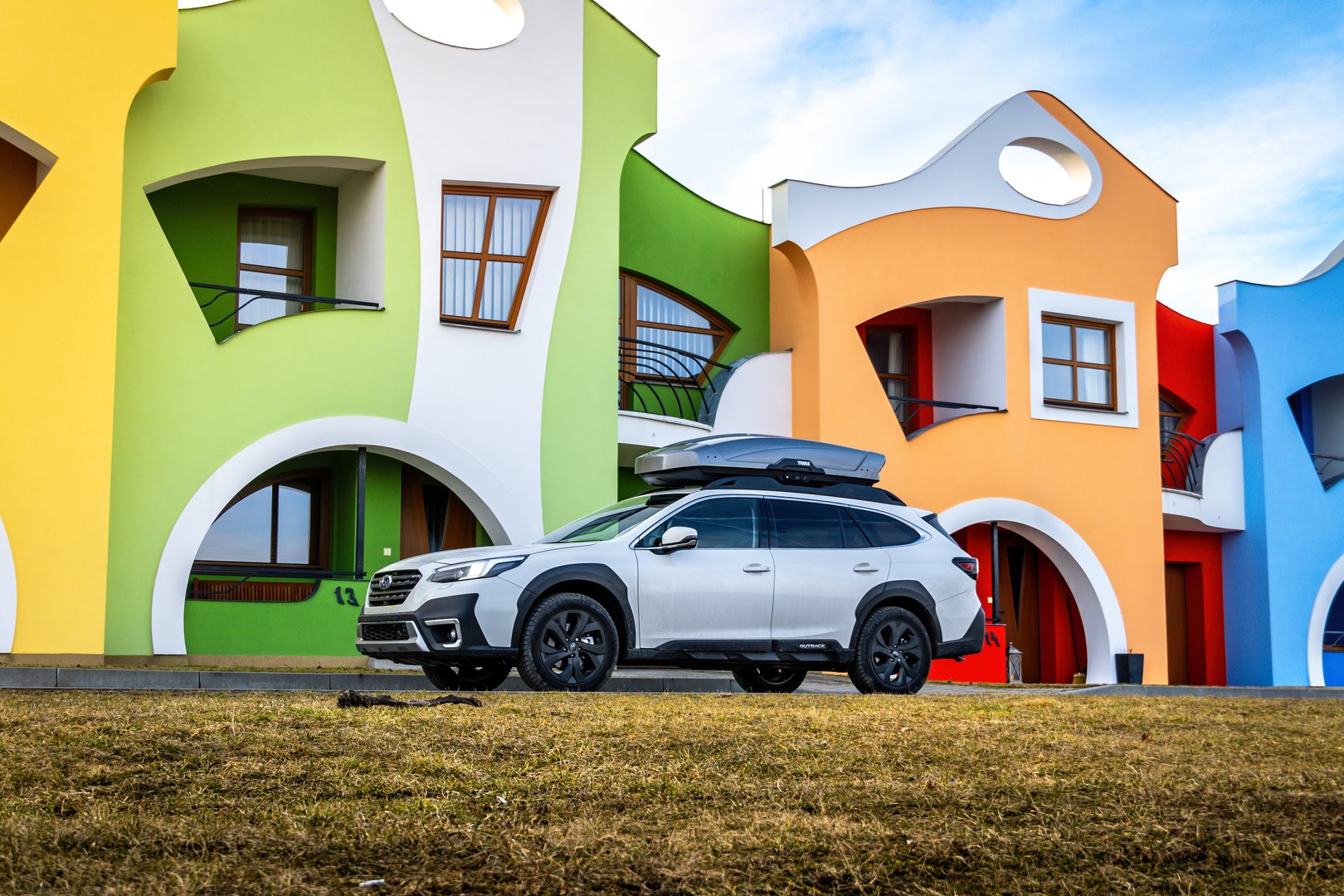 South Moravia, Czech Republic - 06 January 2024: A white Subaru Outback SUV is parked outside in front of colorful houses with crooked windows.