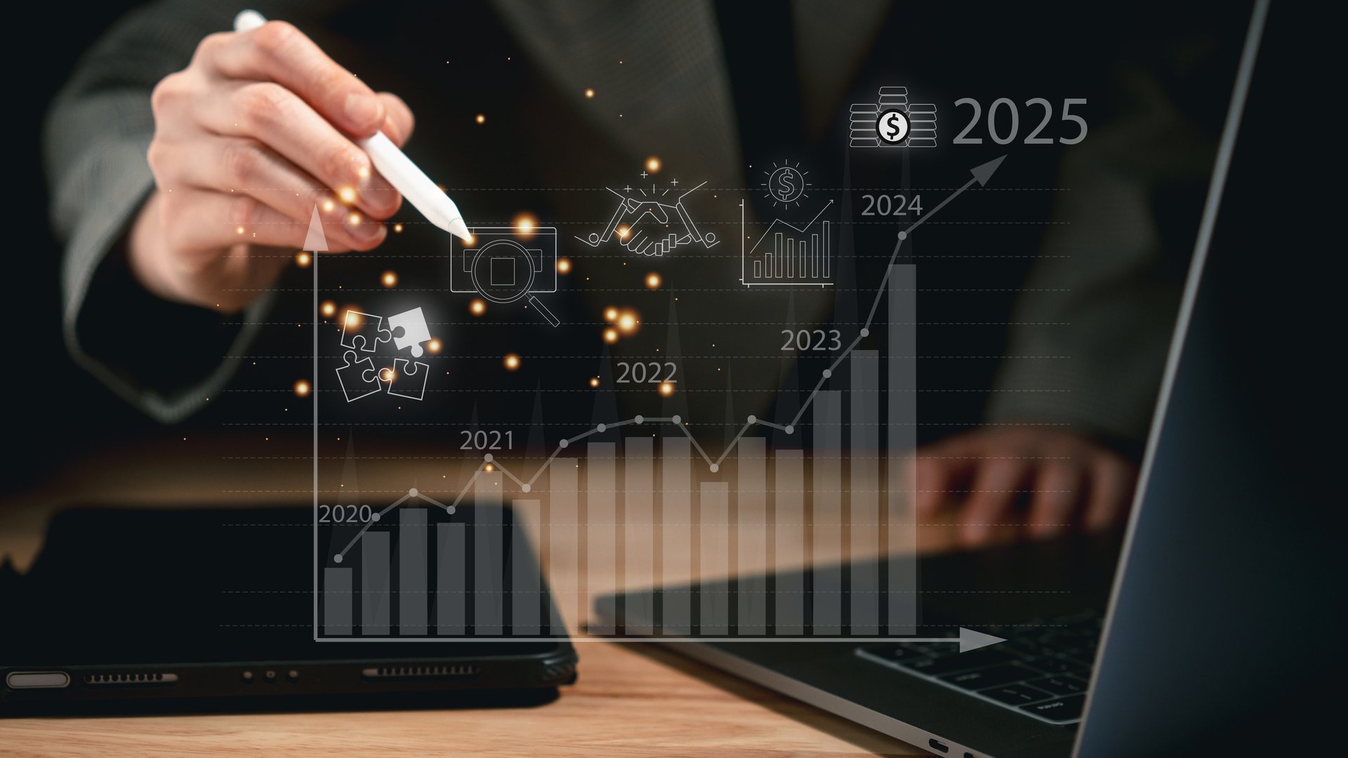 Businessperson using stylus to illustrate future growth strategy with glowing bar graph and financial icons from 2020 to 2025