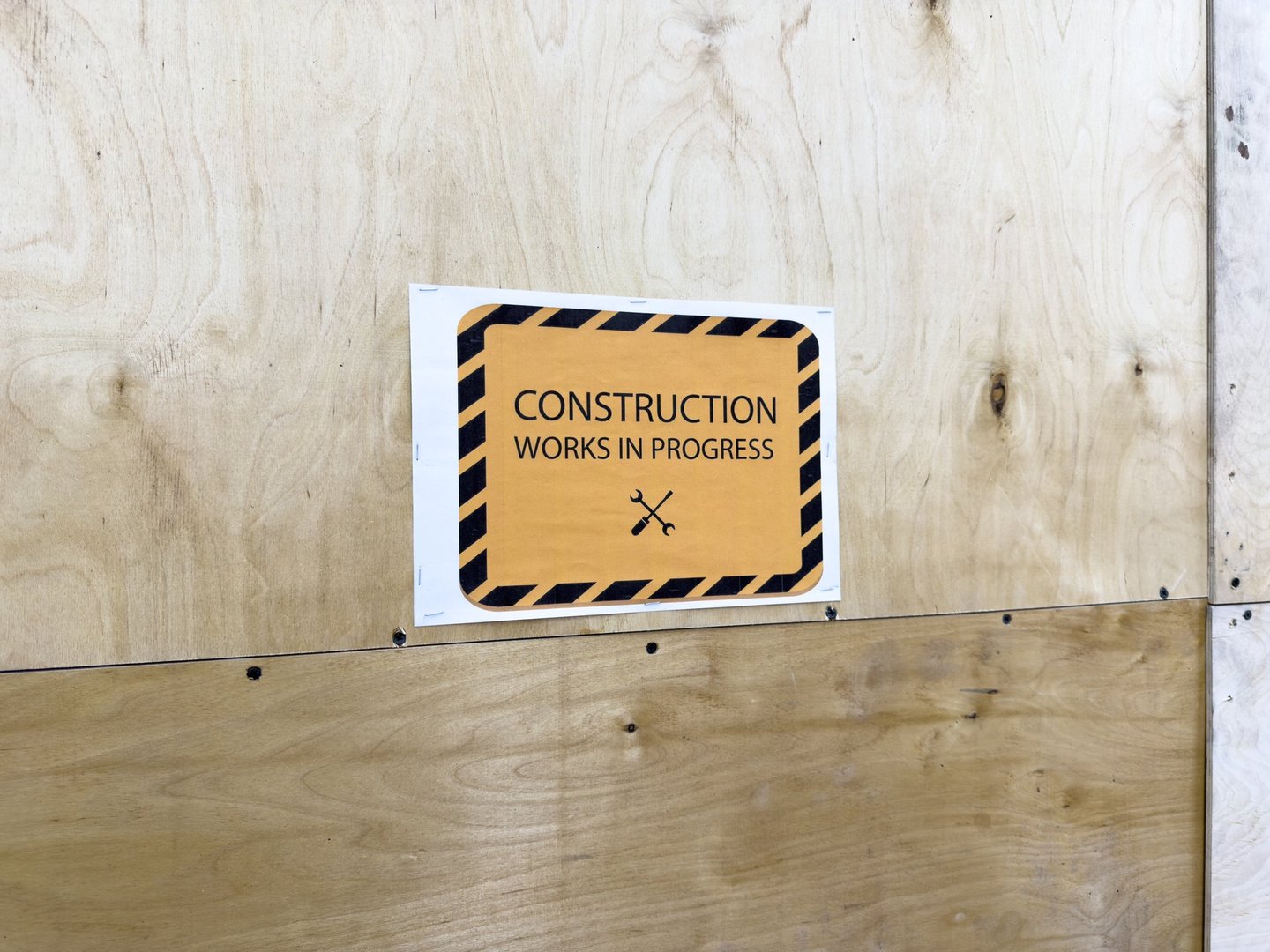 Urban plywood wall with printed construction warning sign, minimalist industrial style element