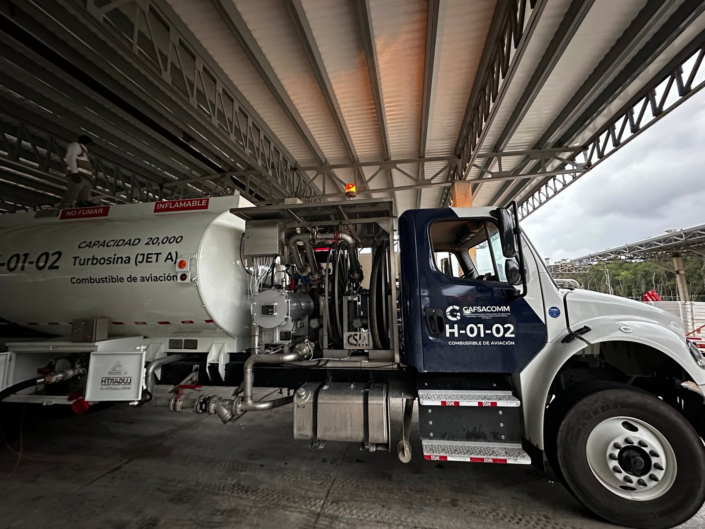 Fuel truck labeled Turbosina (JET A1) parked under a metal roof at an aviation fuel station.