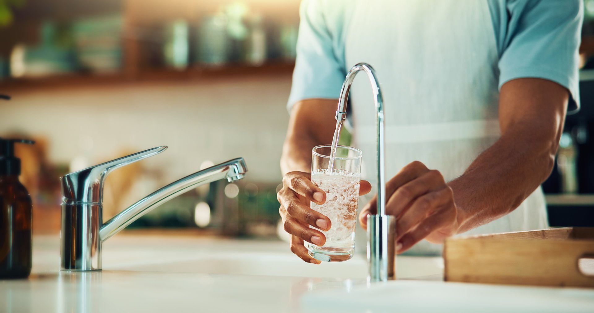 Person, tap and hands with glass of water in kitchen for fresh drink, liquid and hydration. Sink closeup, thirsty or pouring pure beverage in container for nutrition, drinking or filtration in home